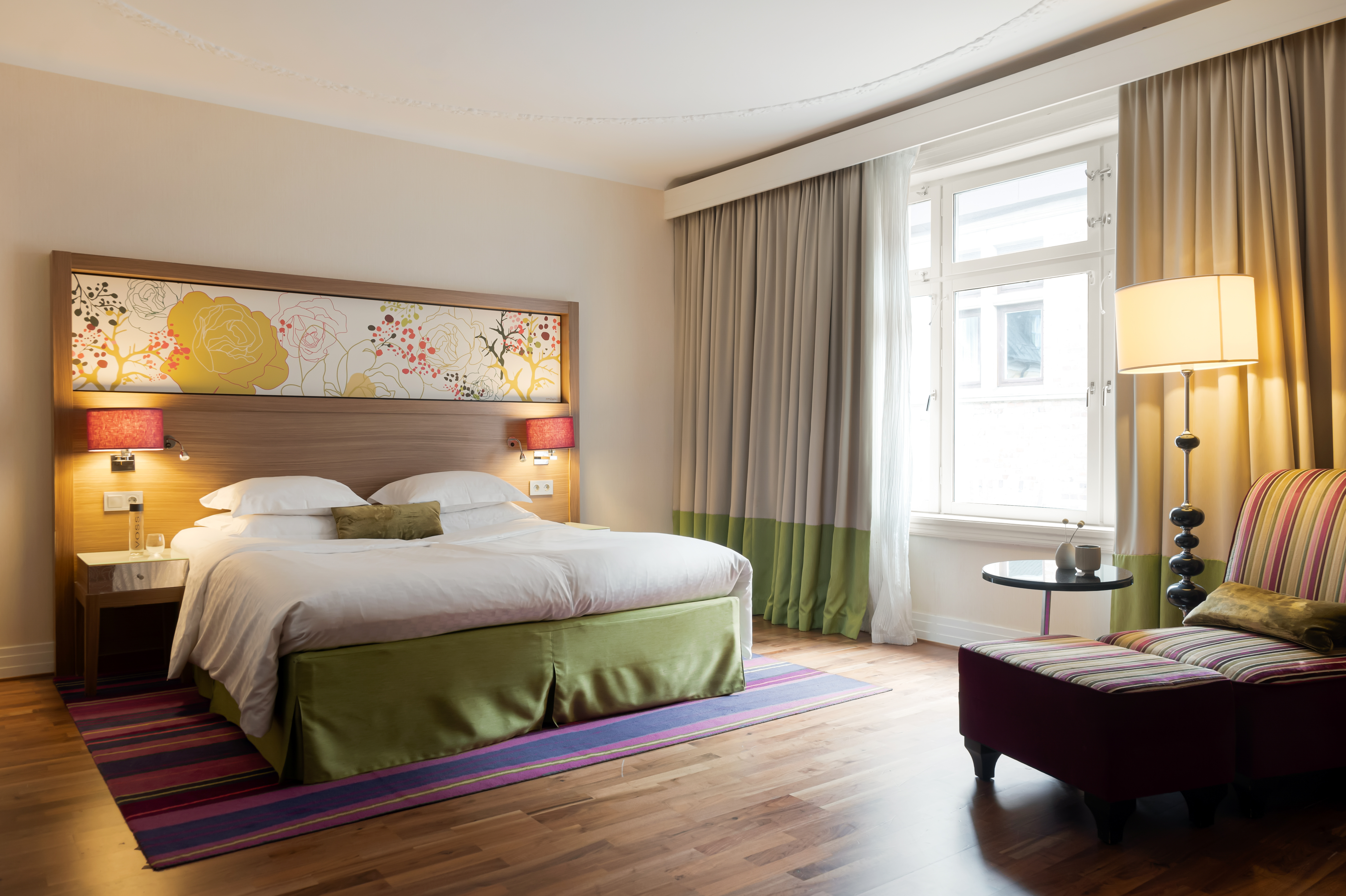 Large hotel room with double bed, armchair and window