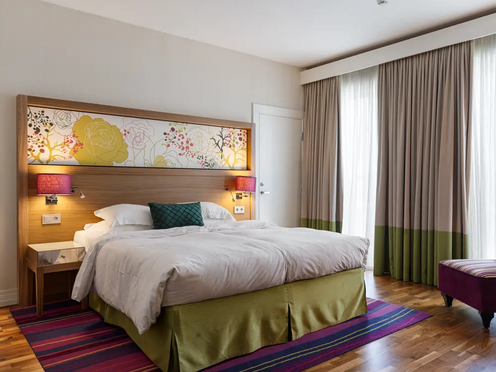 Stort hotellrum med dubbelsäng, fåtölj och fönster