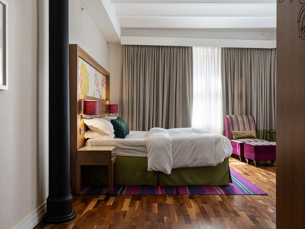 Hotellrum med dubbelsäng, fåtölj och stora fönster