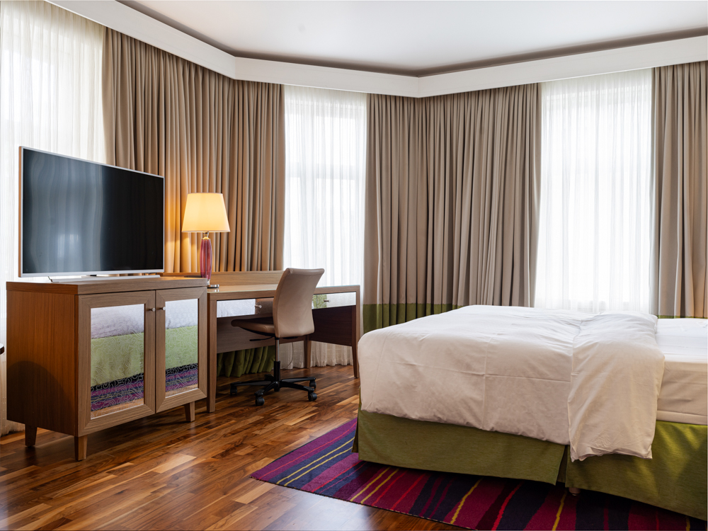 Hotellrum med fåtölj, skrivbord och fönster