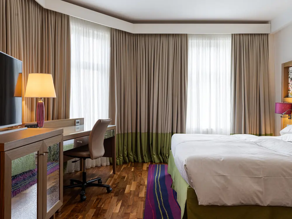 Hotellrum med dubbelsäng, fåtöljer och skrivbord