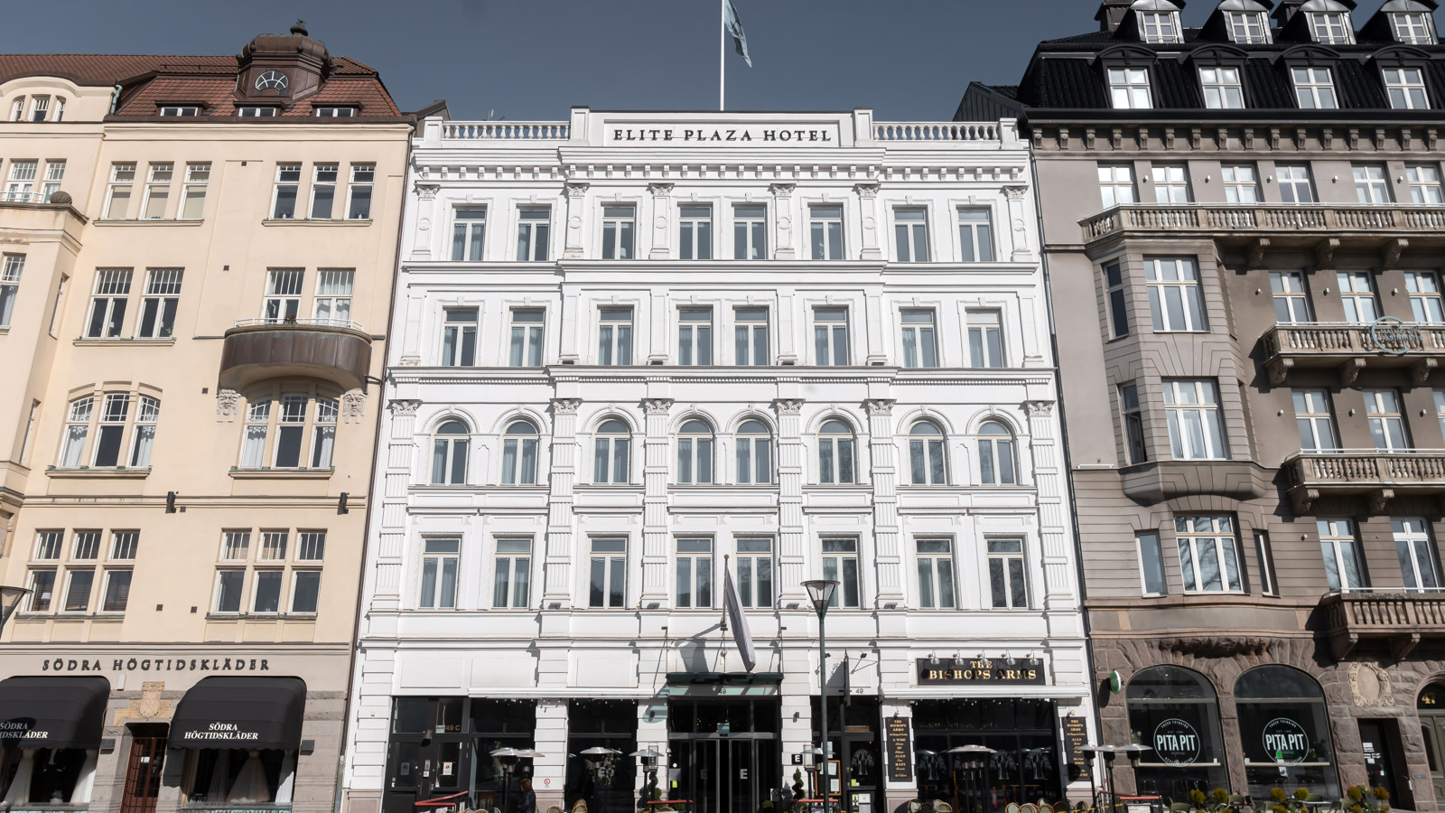 The white facade of the Elite Plaza Hotel in Malmö with a shopping street in front
