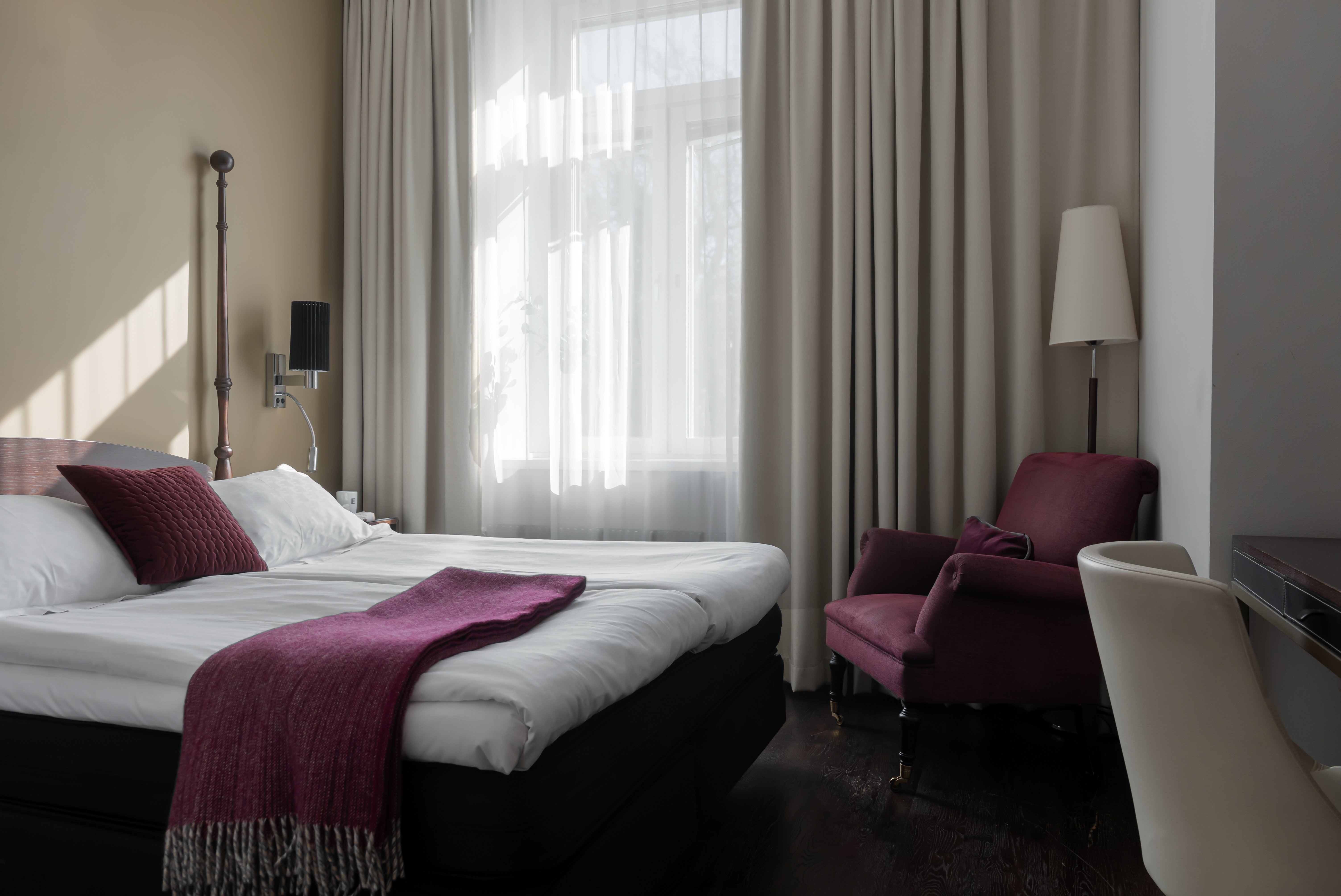 Bright hotel room with bed, armchair and window