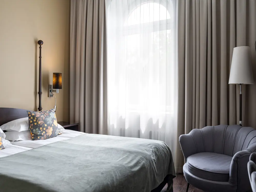 Bright hotel room with bed, armchair and window