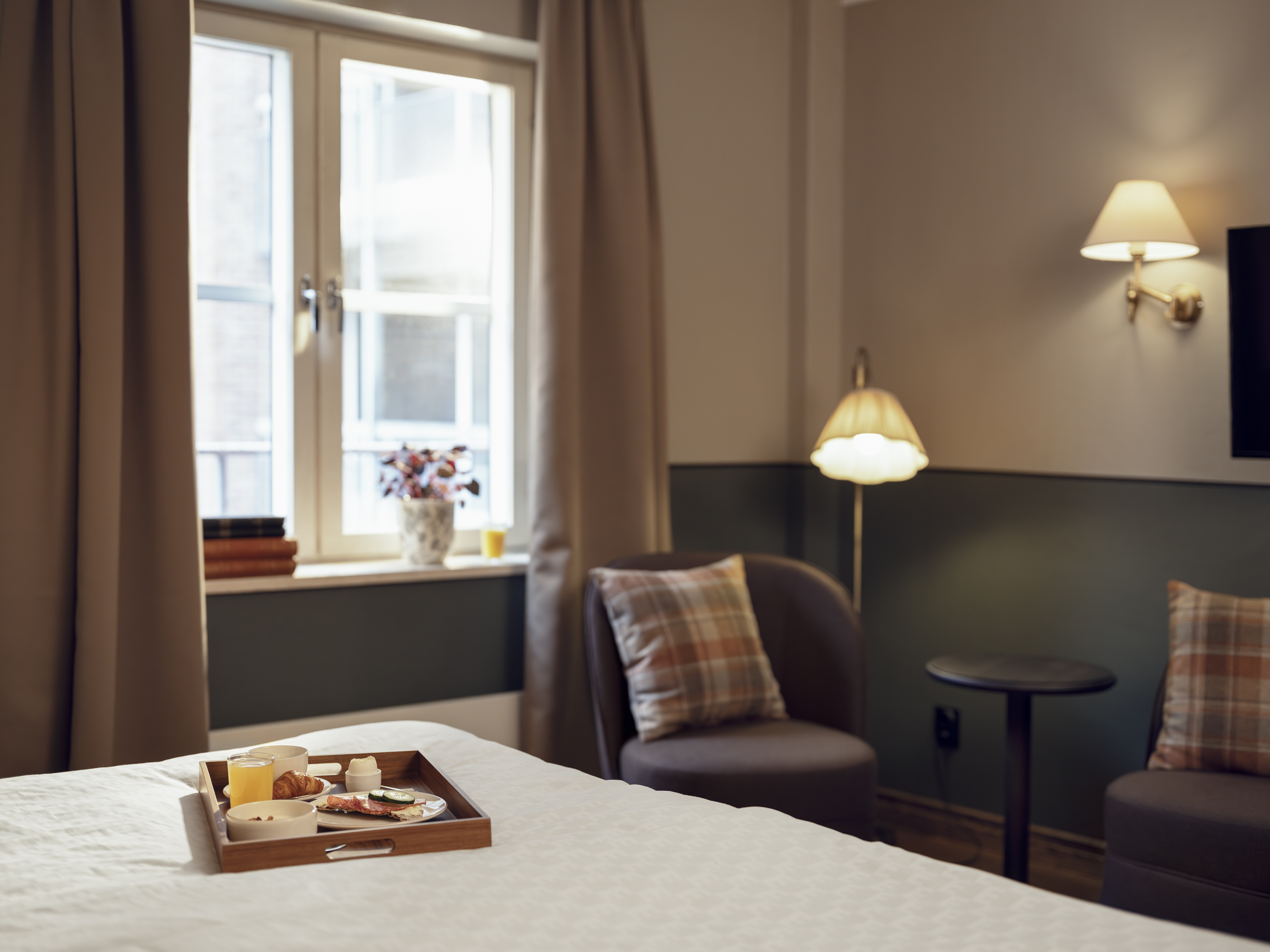 Cozy bedroom with armchairs, table, and window light.