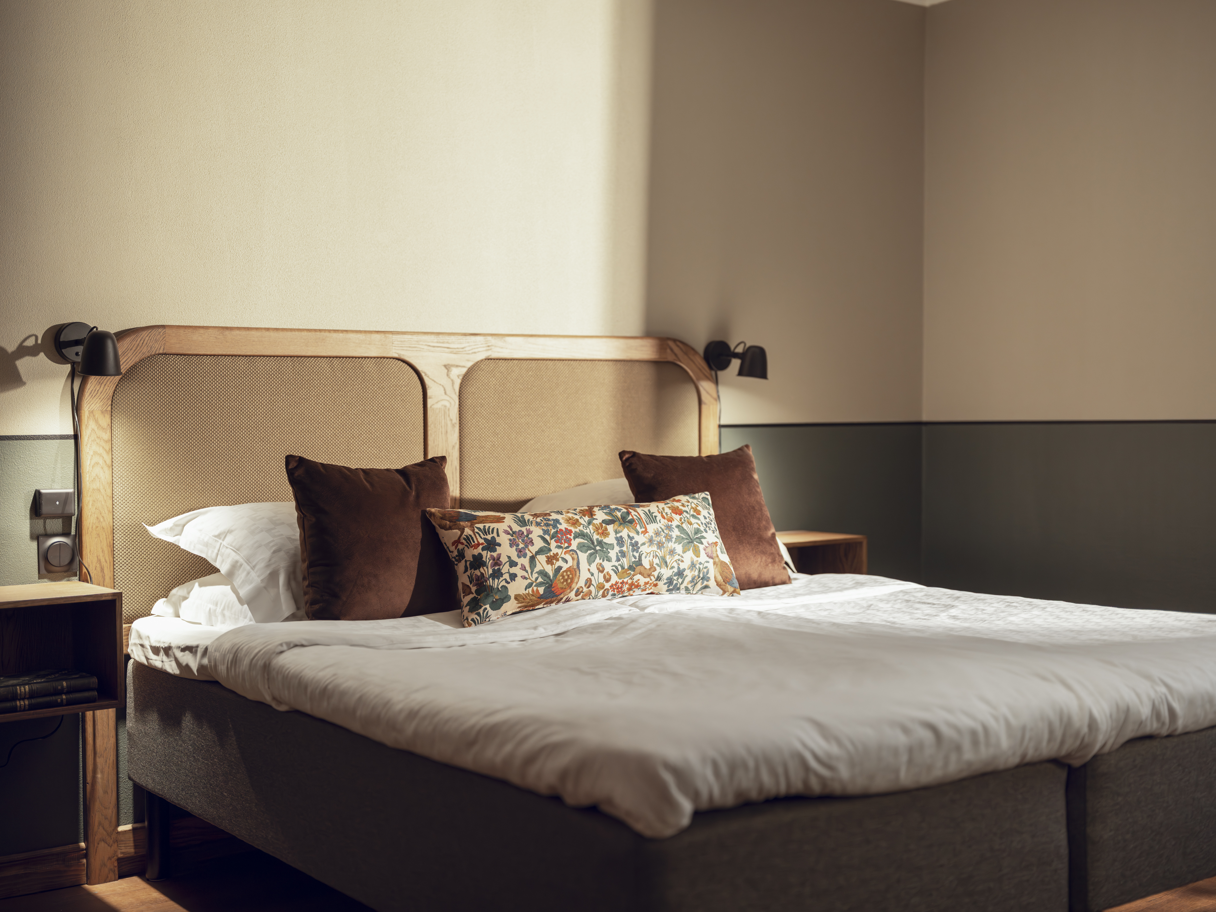 Cozy bedroom with double bed, brown pillows, and wall lamps.