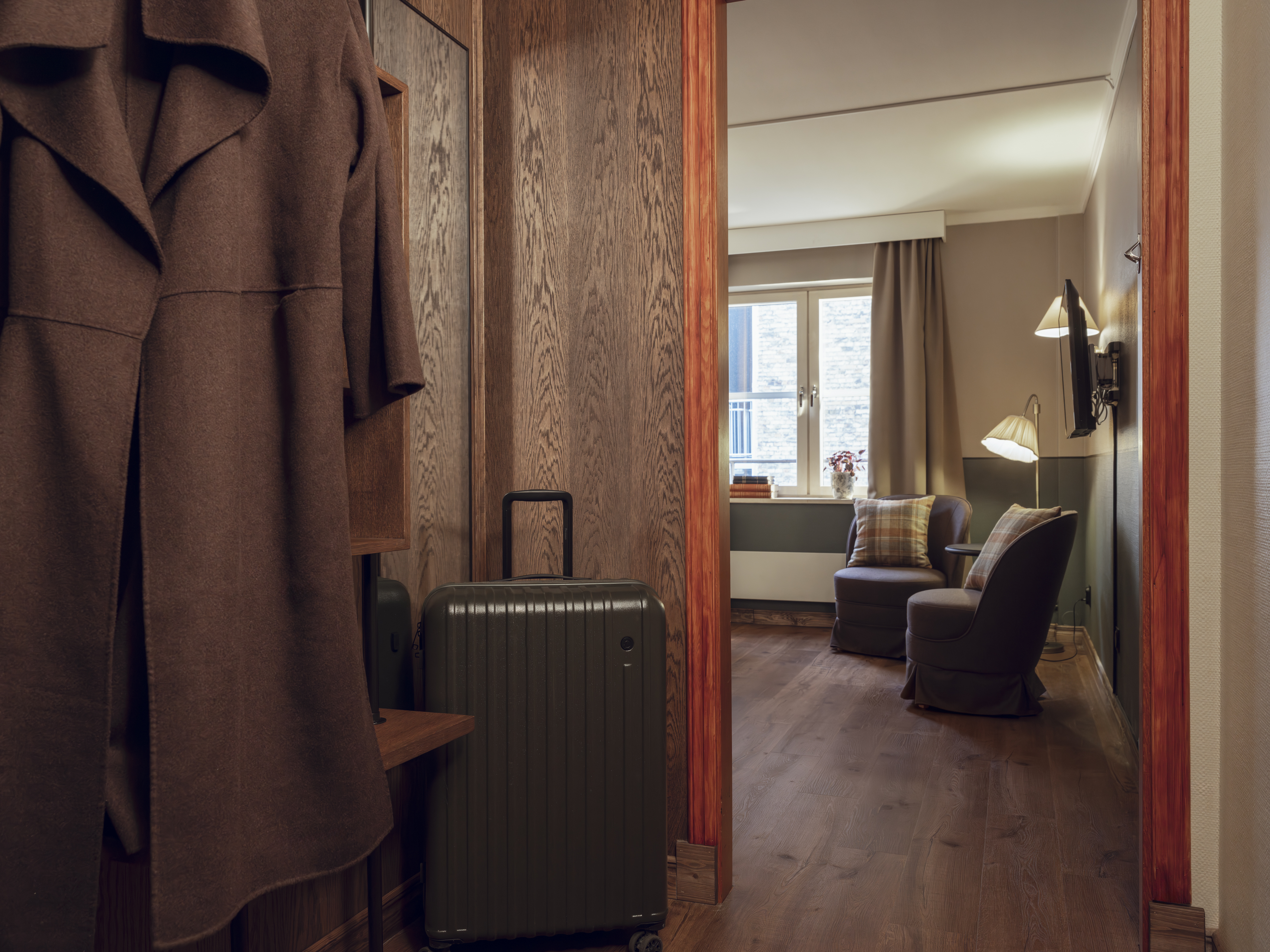 Entrance of a hotel room with a suitcase and seating area.