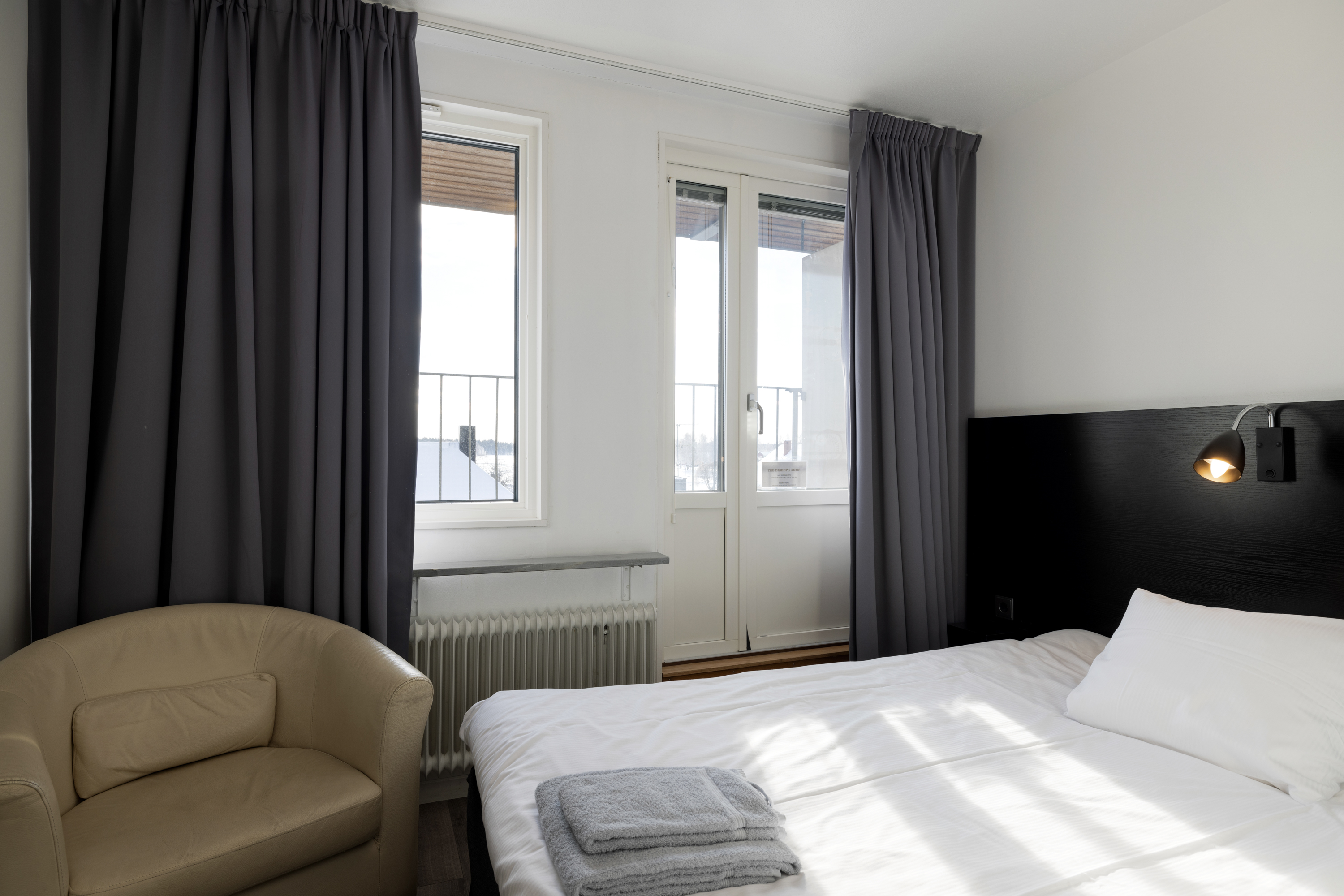 Hotel room with bed, beige leather armchair and balcony