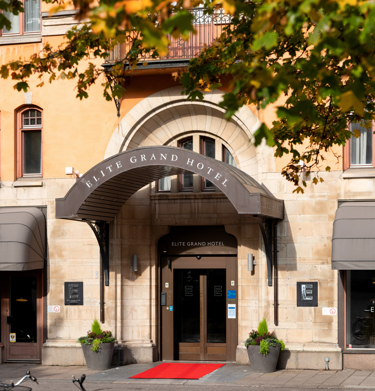 The entrance to the Elite Grand Hotel with a grand ceiling, red carpet and large doors