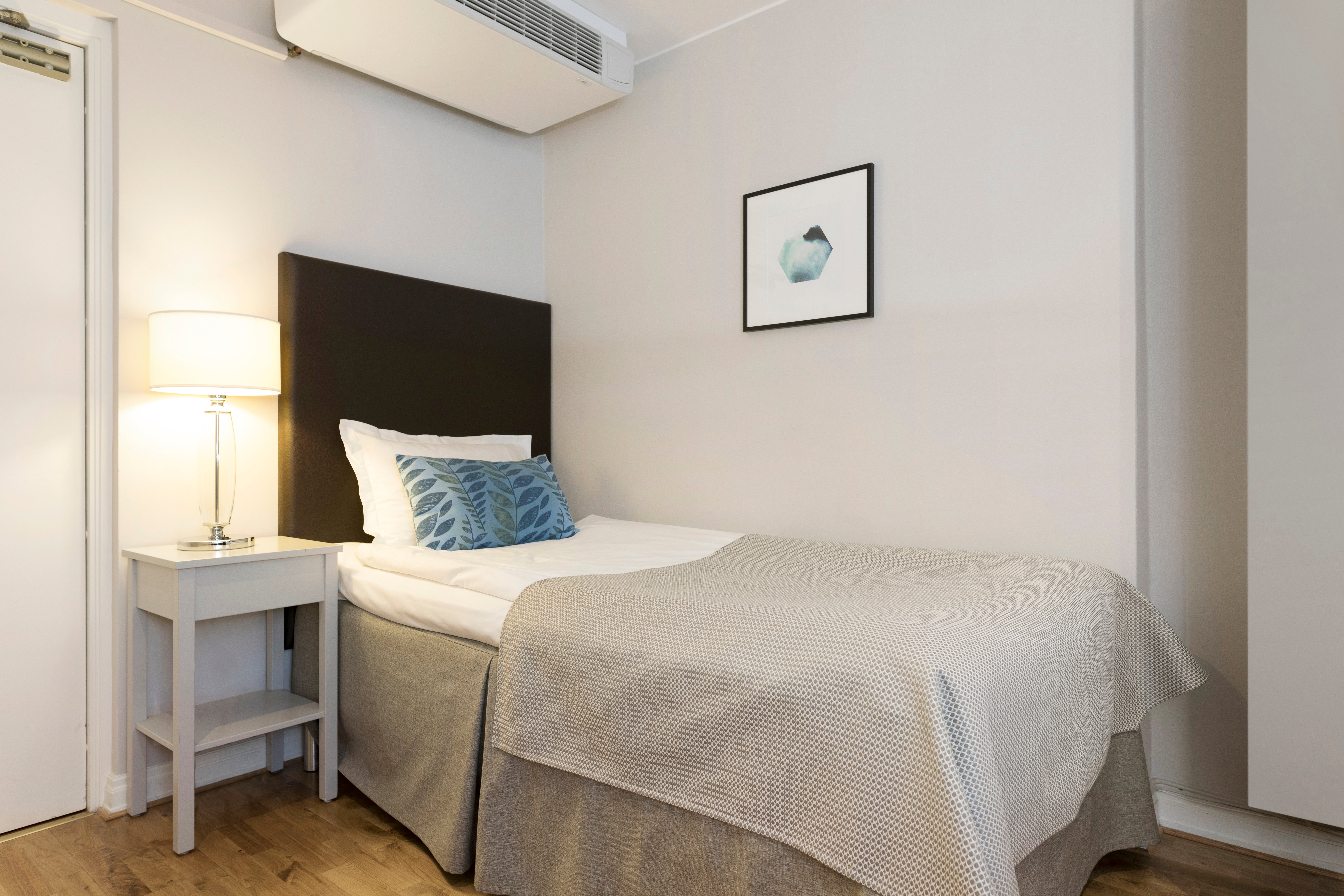 Bright hotel room with bed, bedside table and bedside lamp