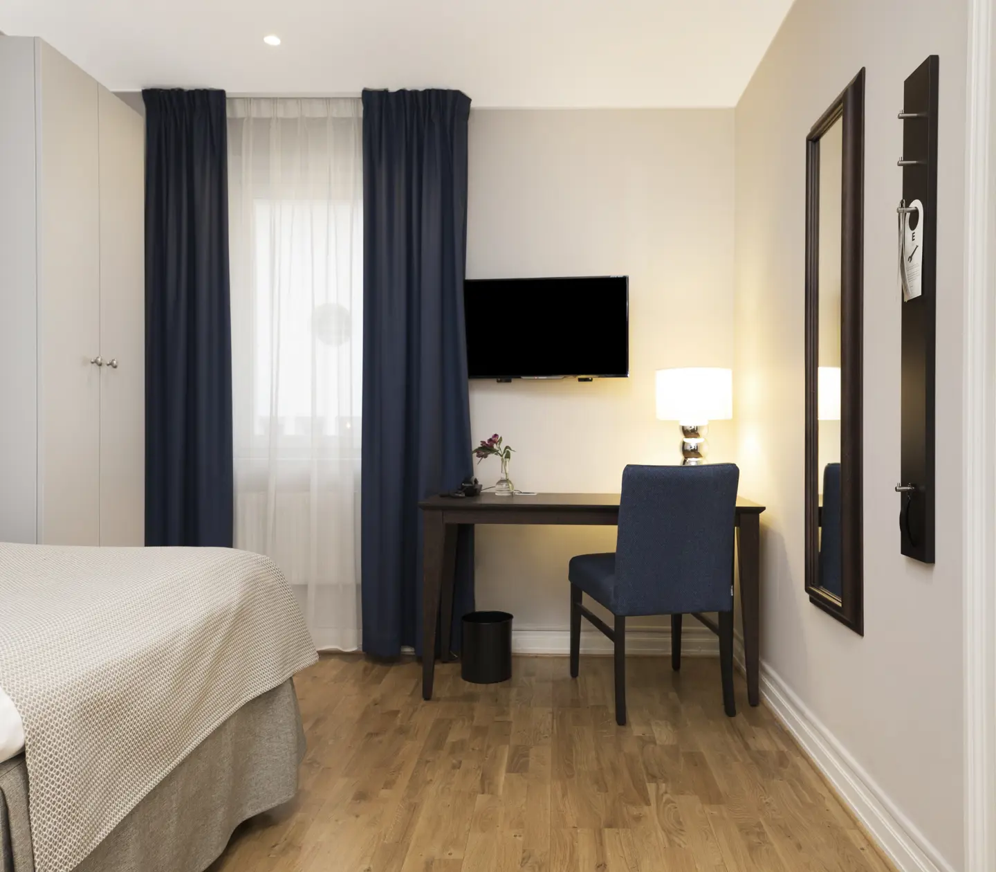 Ljust hotellrum med säng, garderob och skrivbord