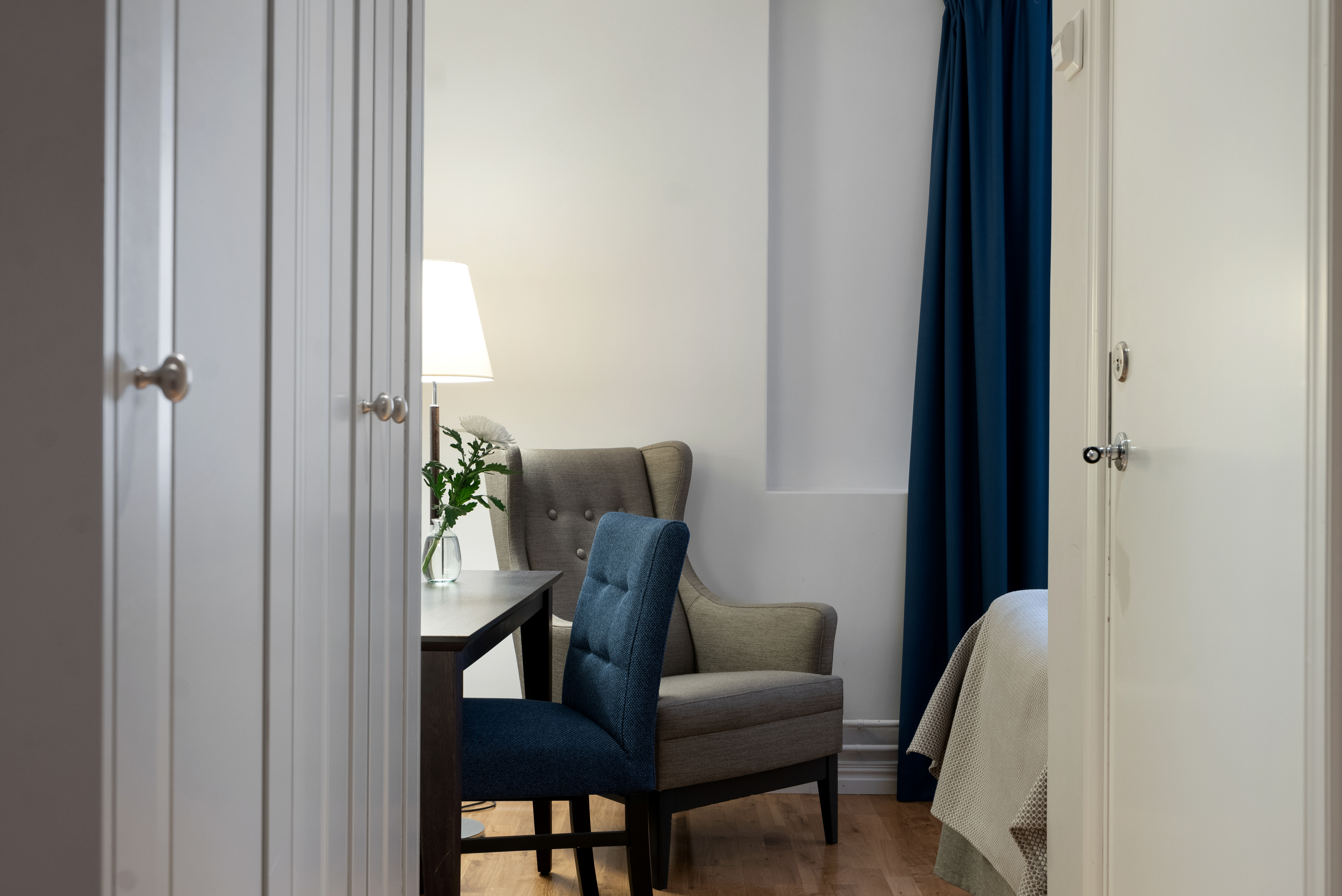 Bright hotel room with armchair, desk and wardrobe