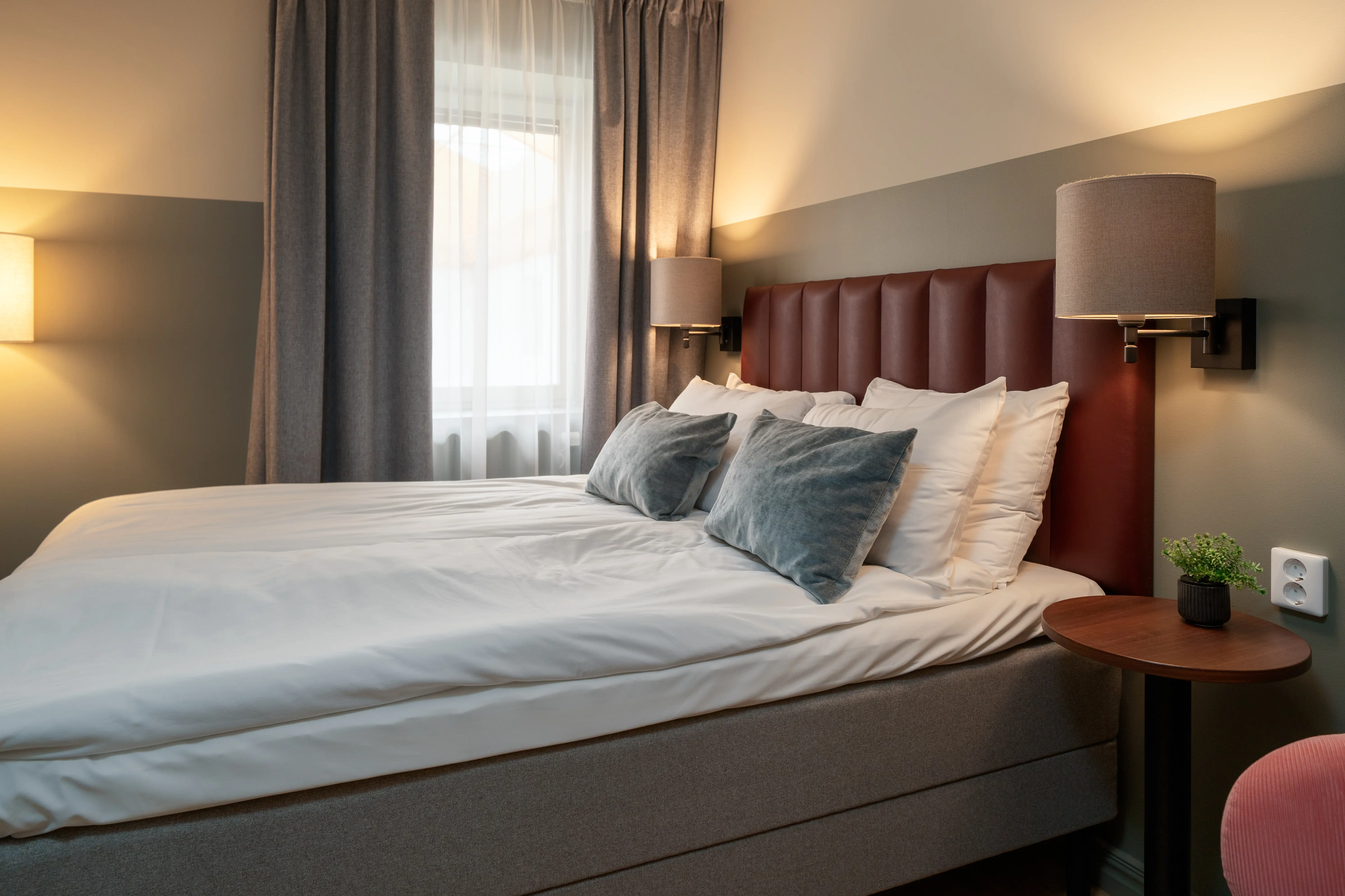 Ombonat hotellrum med dubbelsäng, sänglampor och fönster