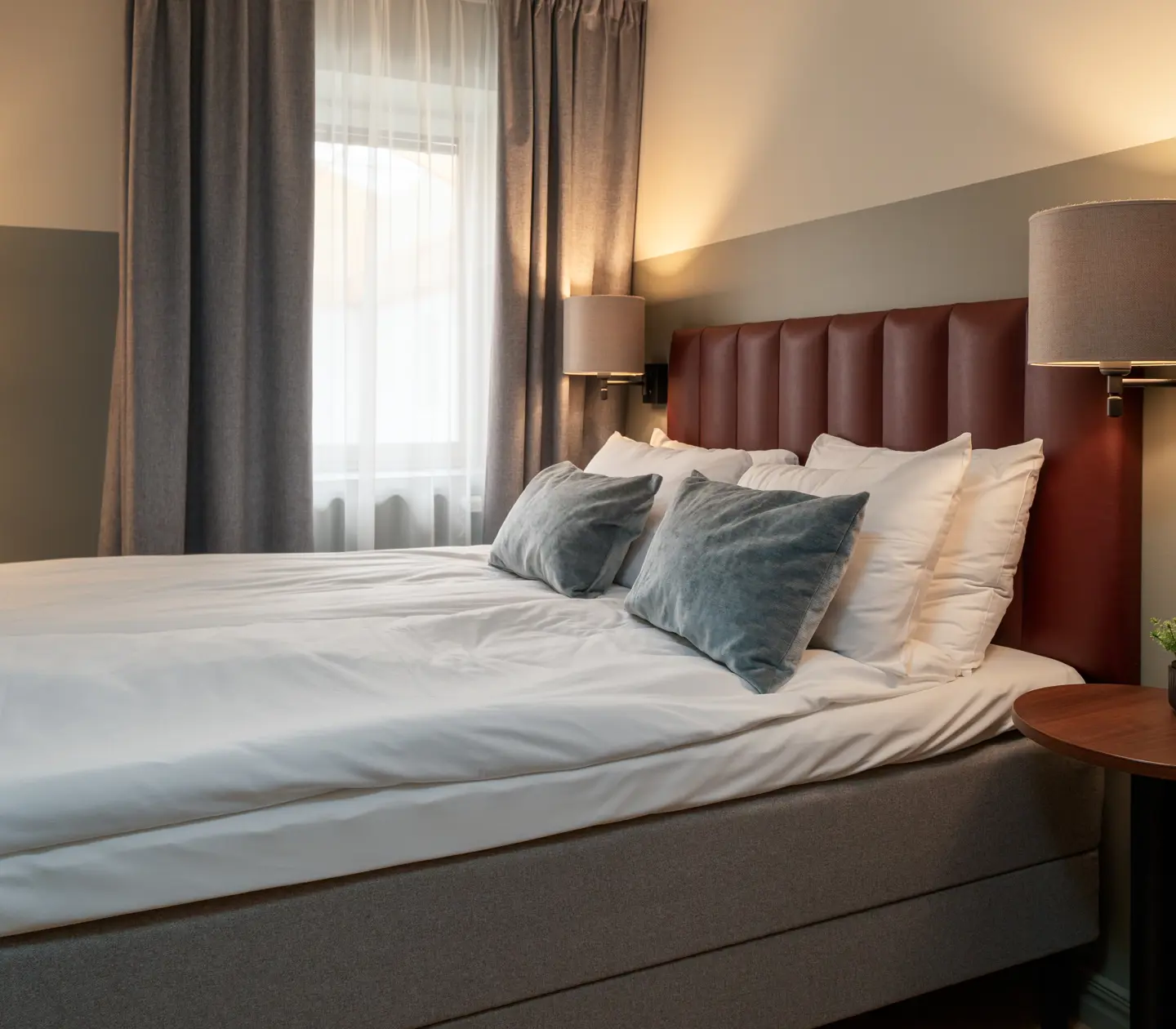 Ombonat hotellrum med dubbelsäng, sänglampor och fönster