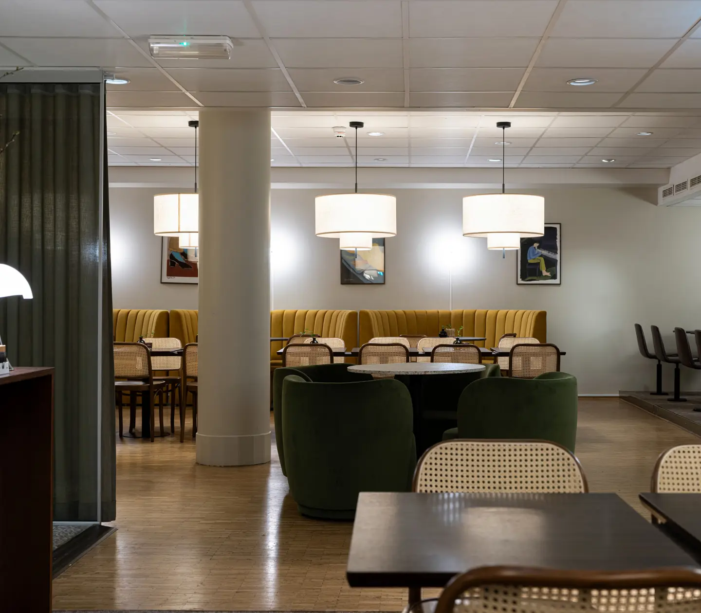 Modern restauranginteriör med eleganta möbler, inklusive gröna och gula sittplatser samt stora hängande lampor