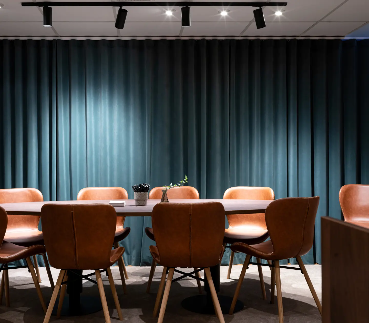 Konferensrum med blå väggar och stolar i styrelsesittning