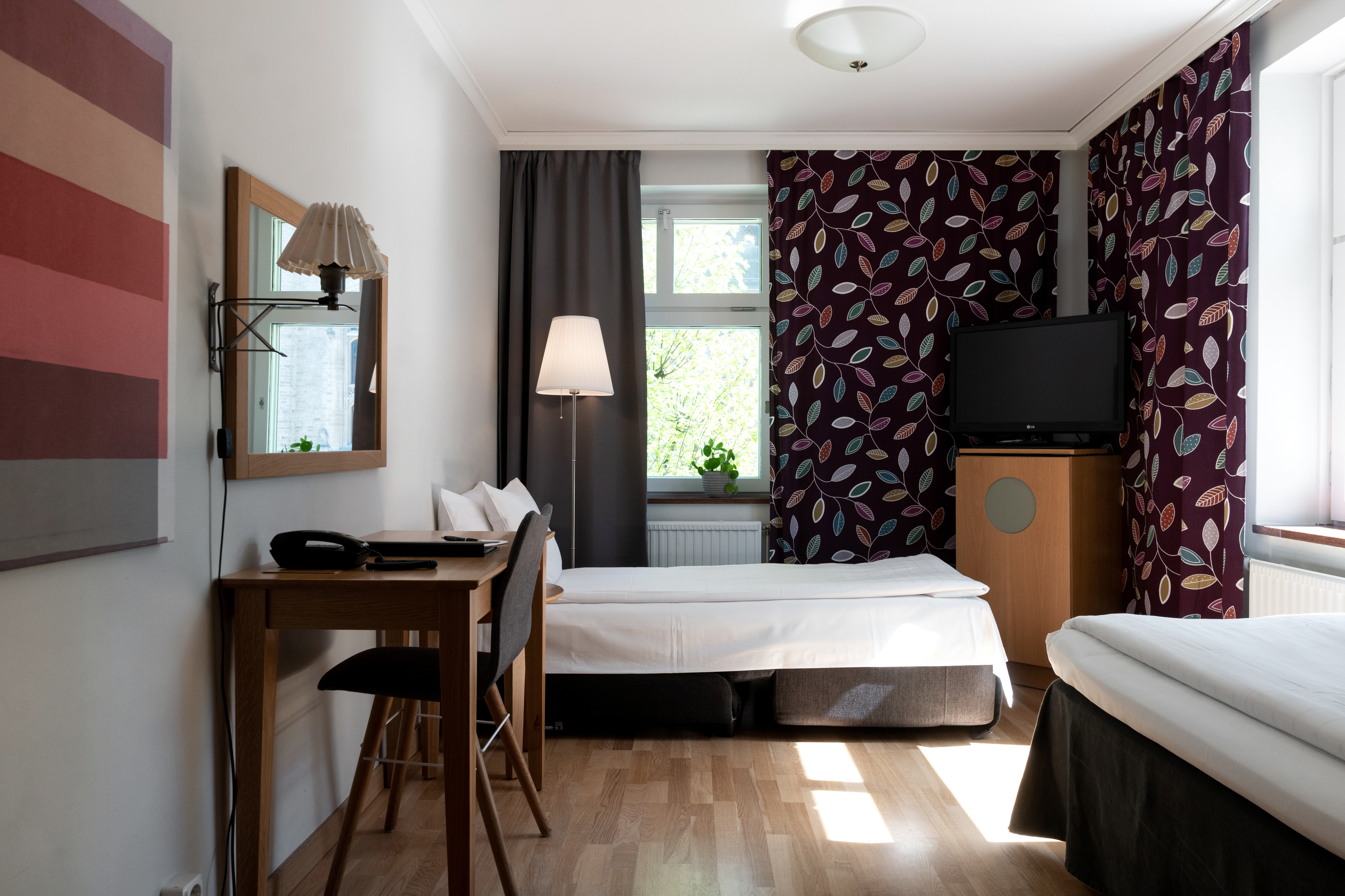 Hotellrum med två enkelsängar, skrivbord och fönster