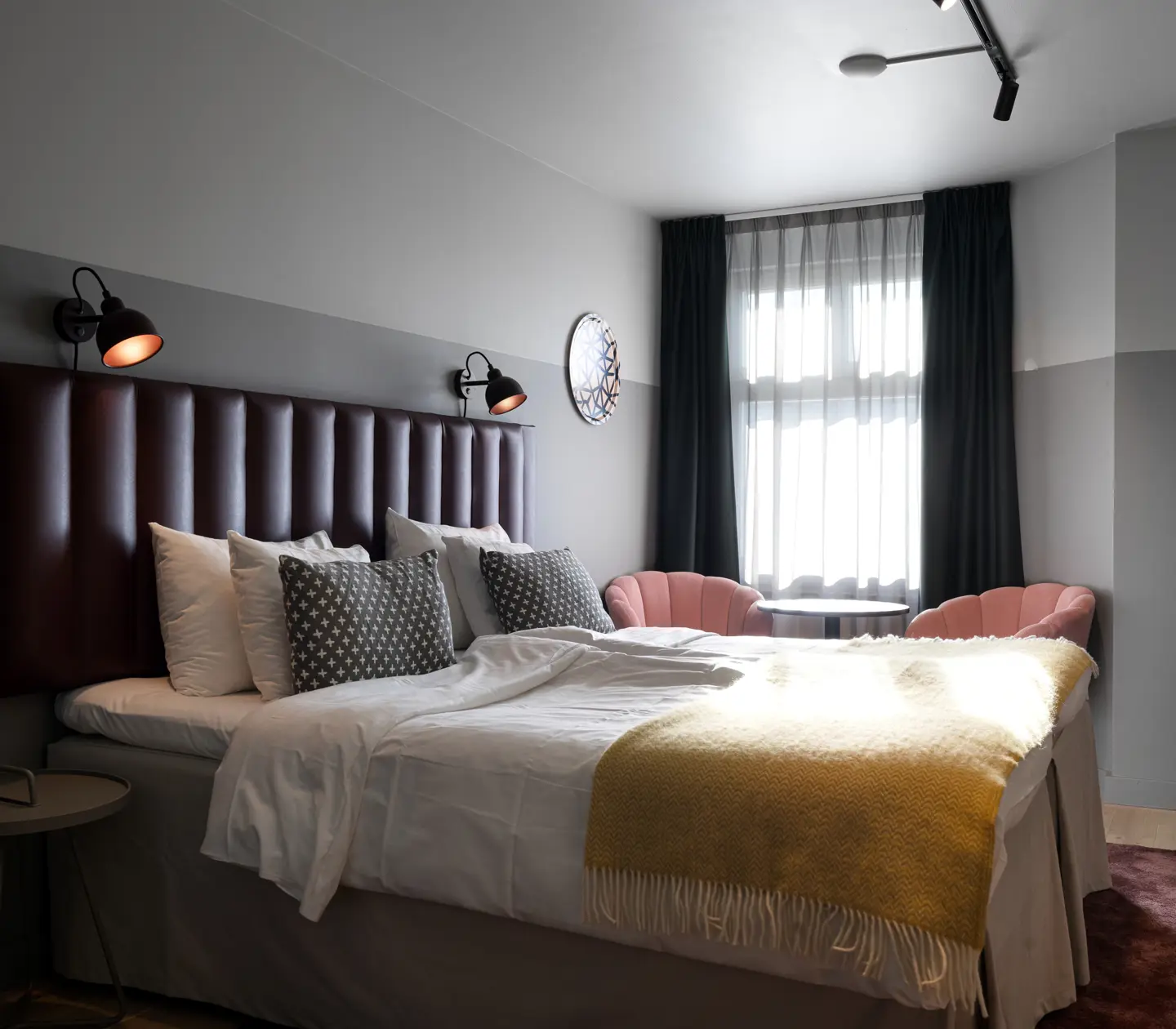 Hotellrum med dubbelsäng, fåtöljer och fönster