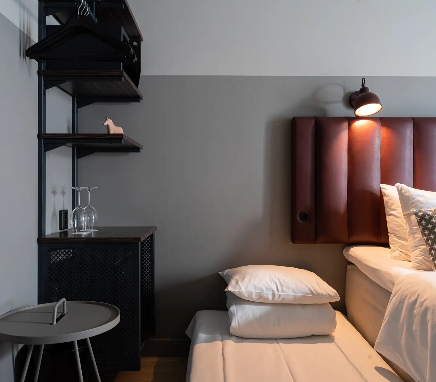 Modernt hotellrum med sänglampa, hyllor och mysig belysning