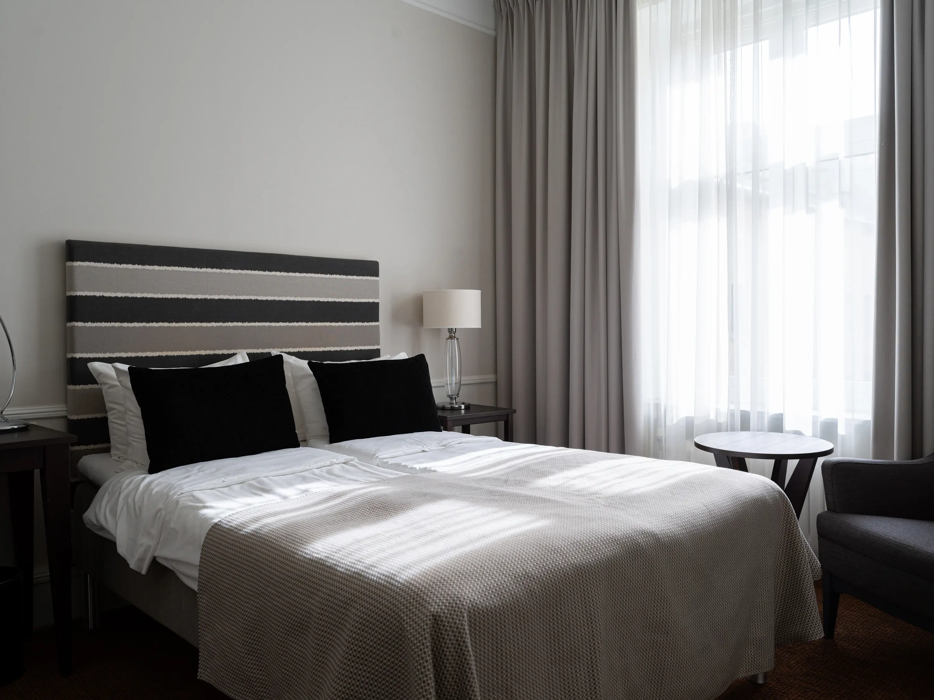 Hotellrum med dubbelsäng, fåtölj och fönster