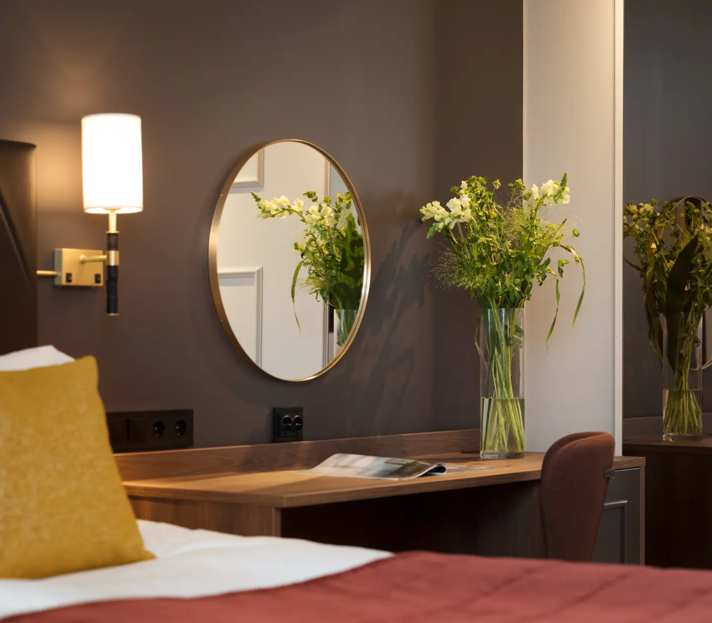 Hotellrum med dubbelsäng, skrivbord, bukett och spegel