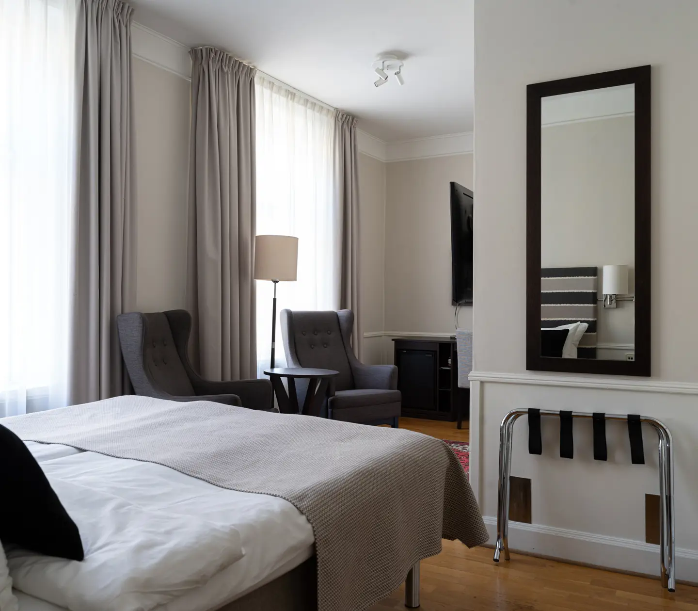 Hotel room with double bed, mirror, desk and TV