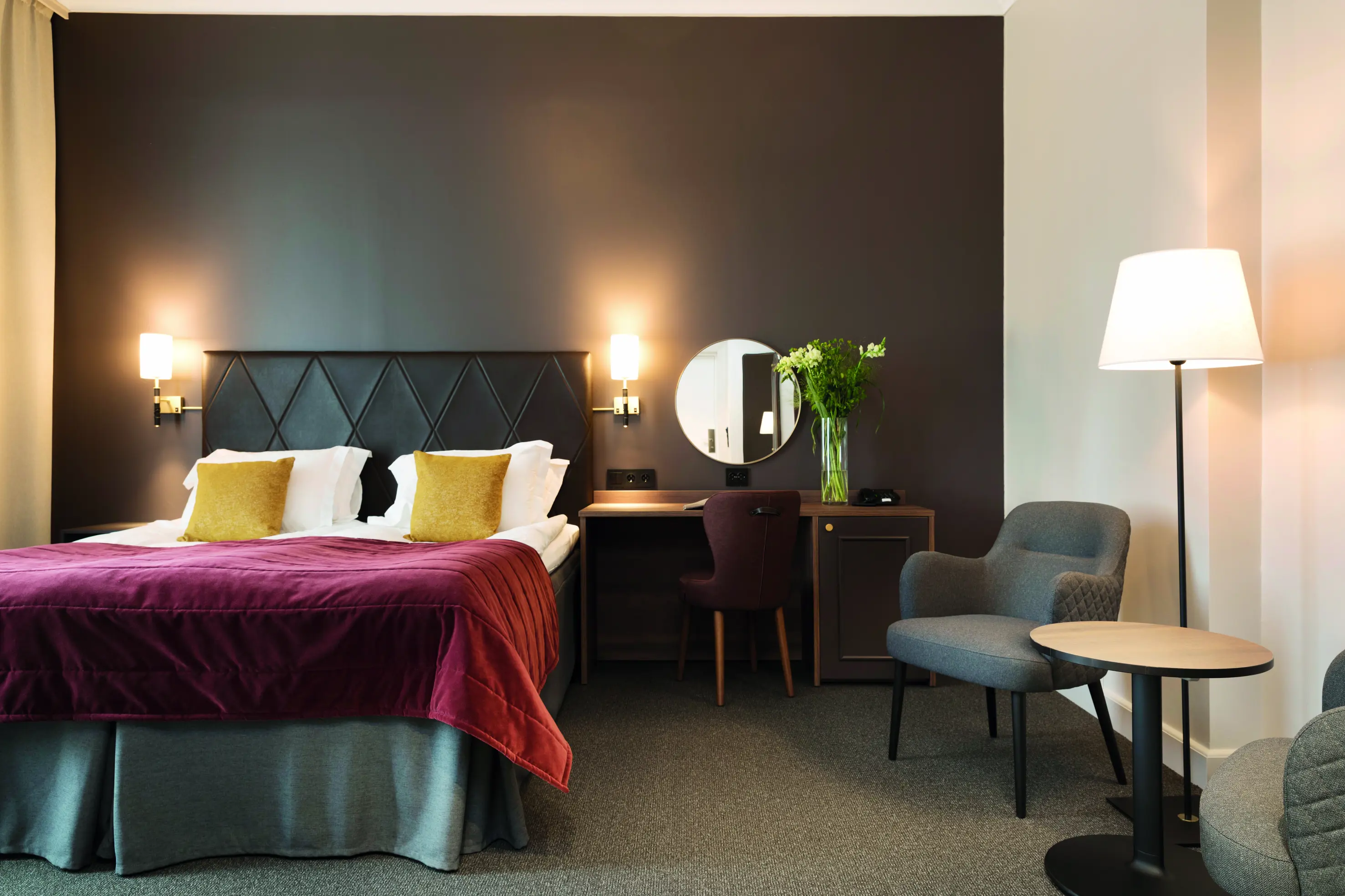 Ljust hotellrum med dubbelsäng, fåtölj och fönster