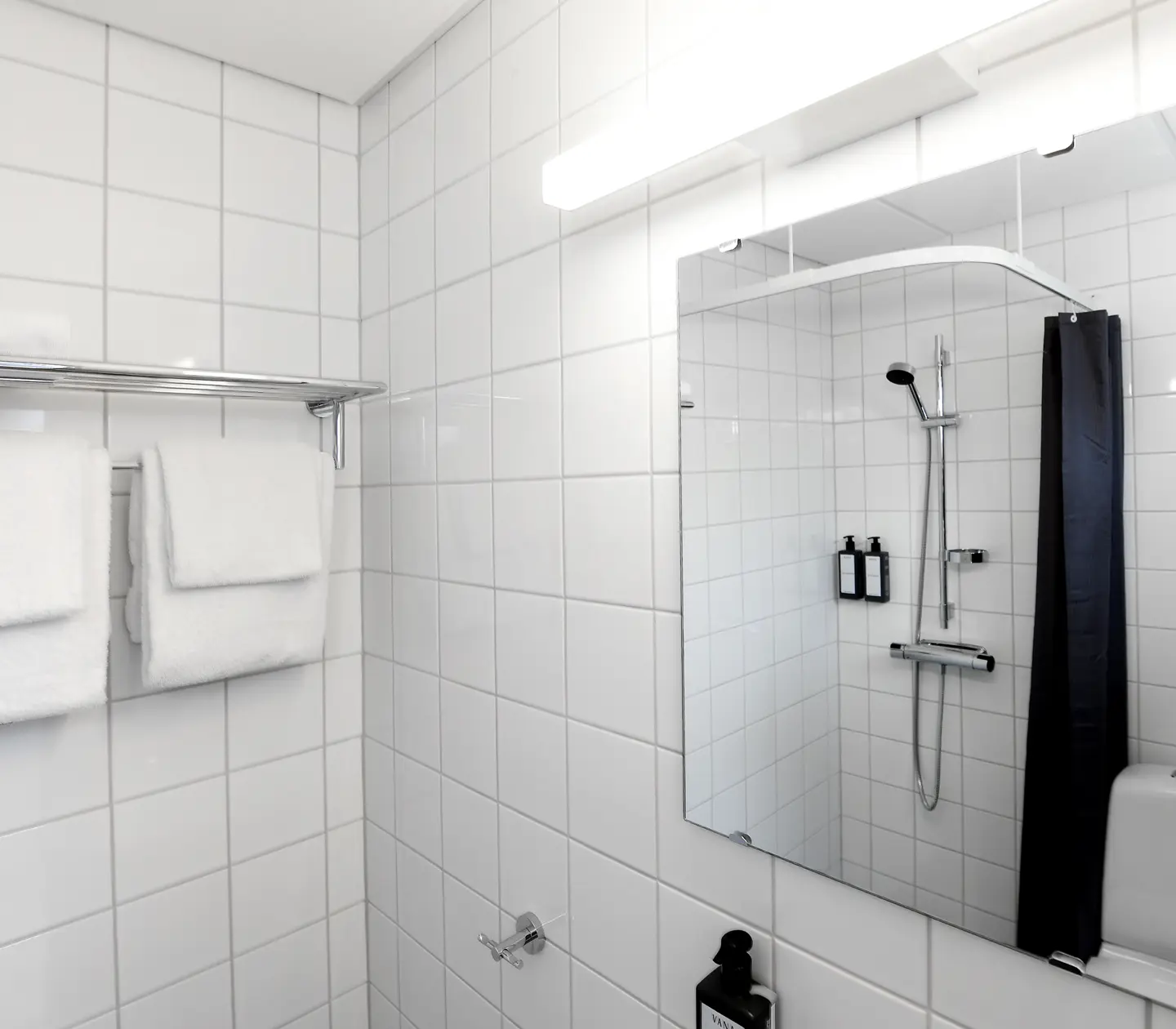 Ljust hotellrum med spegel, toalett och dusch