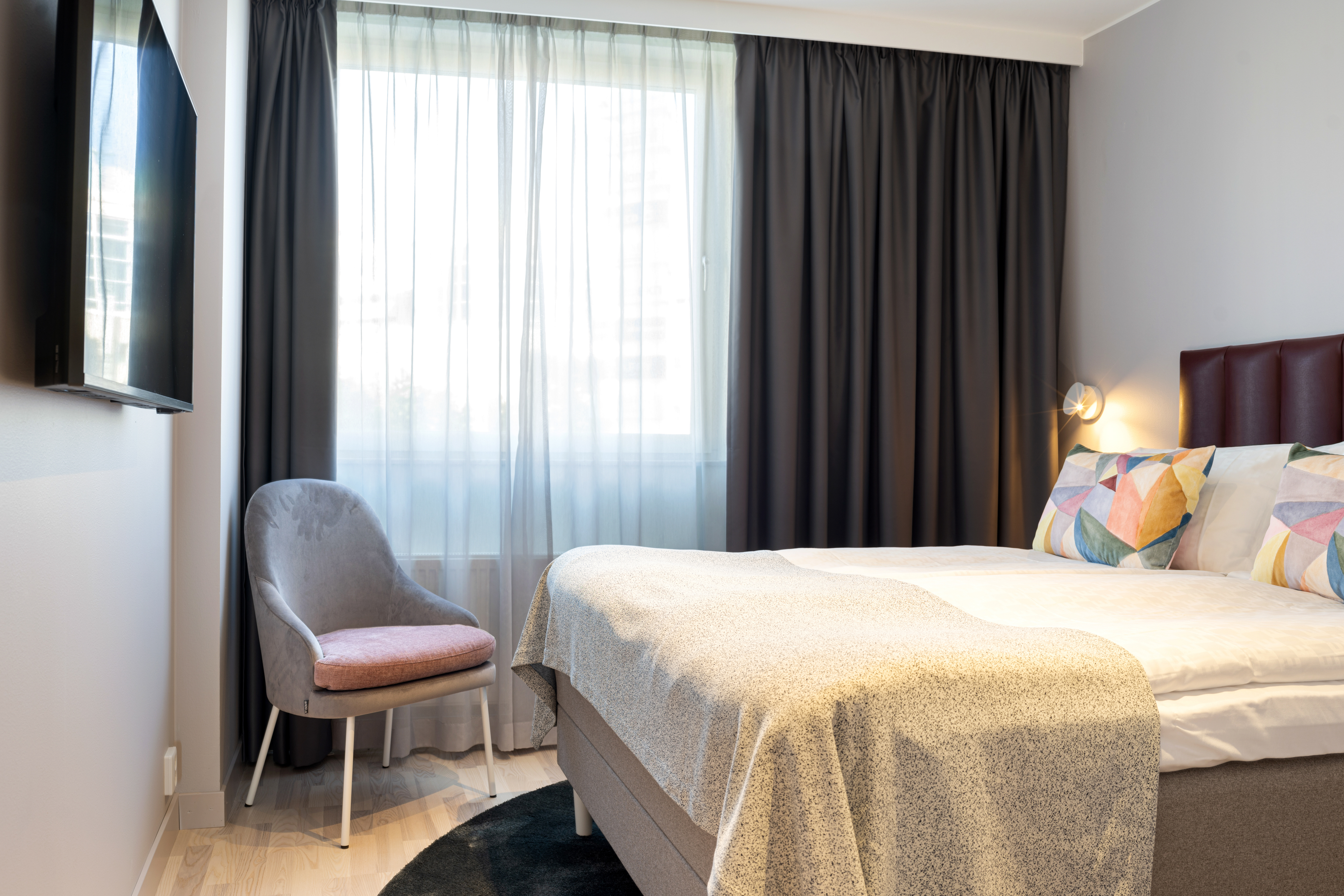Fint hotellrum med dubbelsäng, tv och fönster