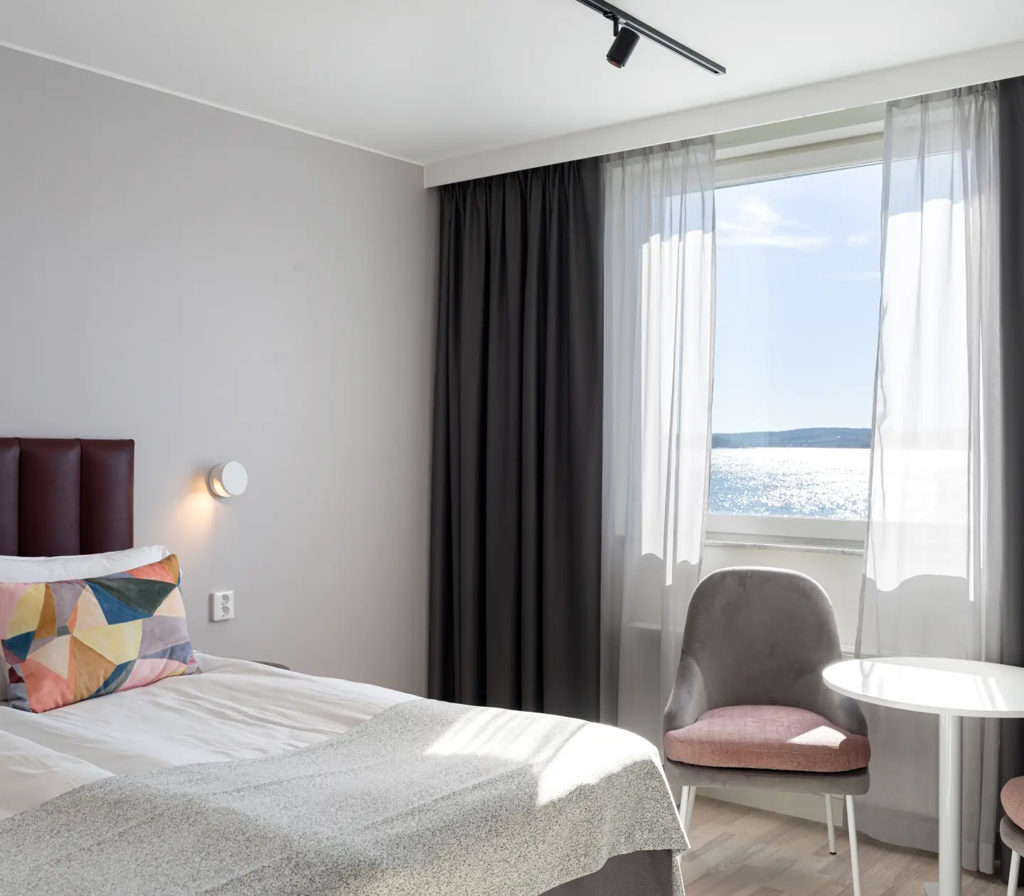 Mysigt hotellrum med dubbelsäng, stolar och fönster
