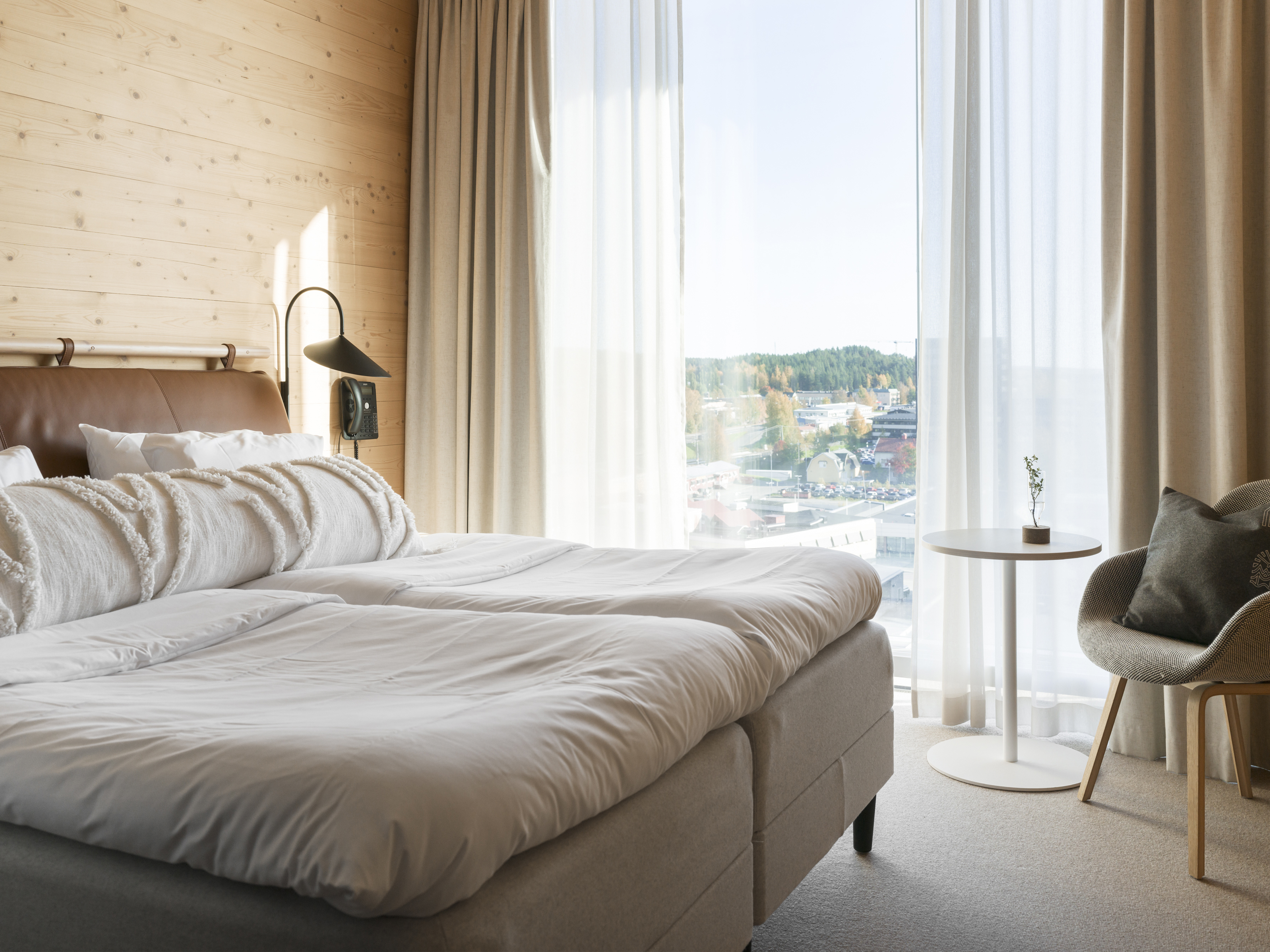 Mysigt hotellrum med säng, fåtöljer och stort fönster