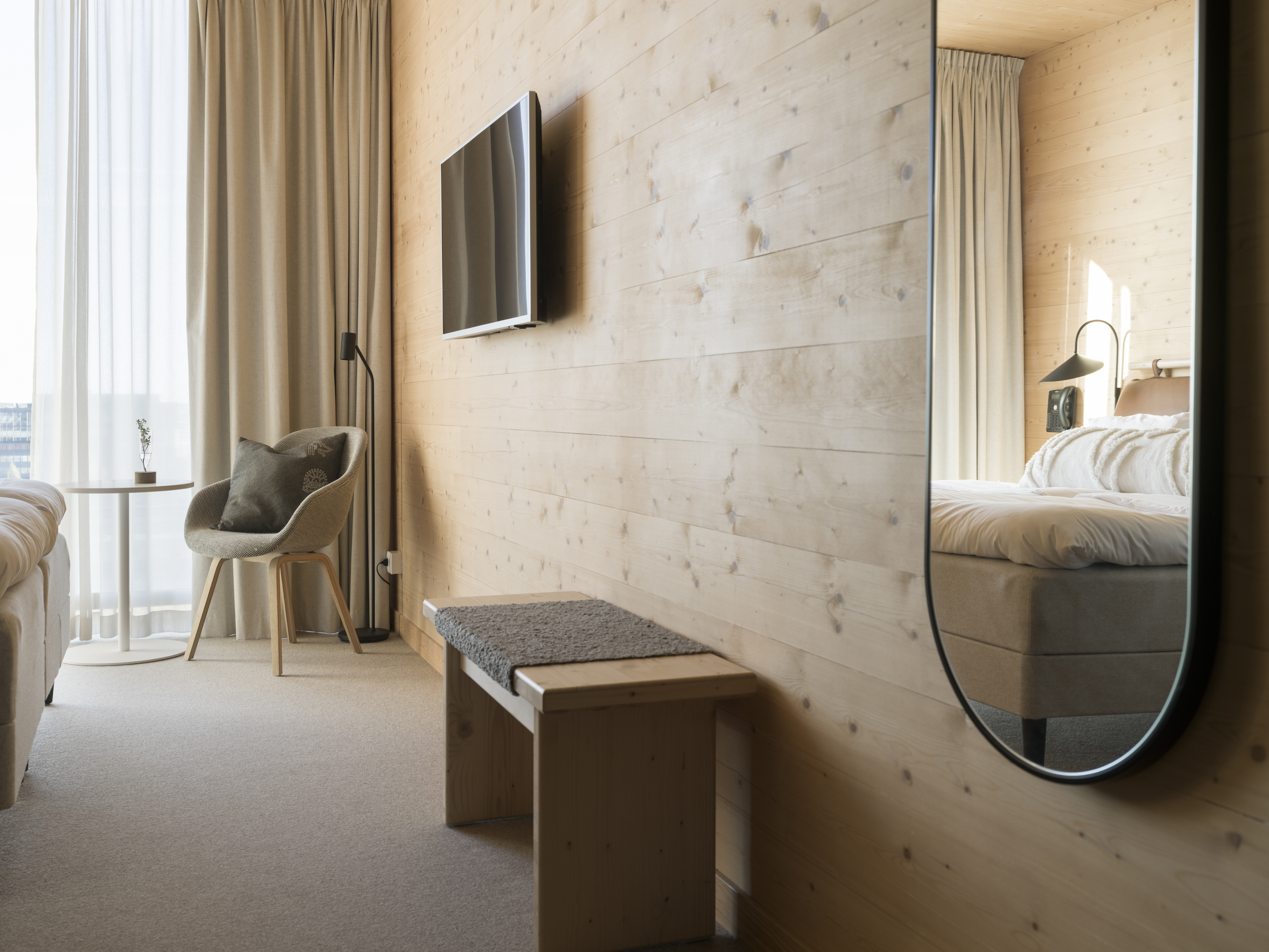 Mysigt hotellrum med säng, spegel och stort fönster