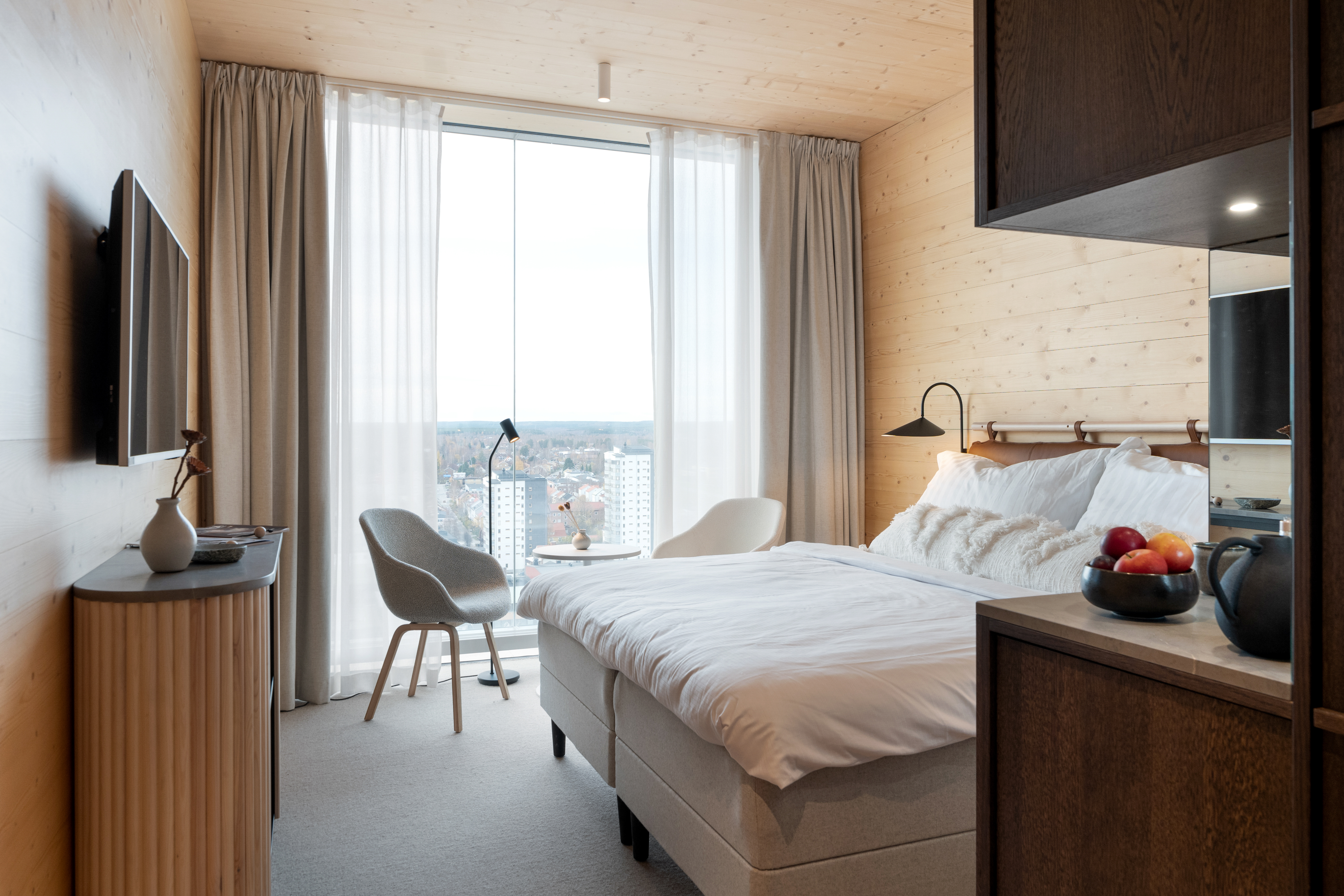 Cozy hotel room with bed, armchairs and large window