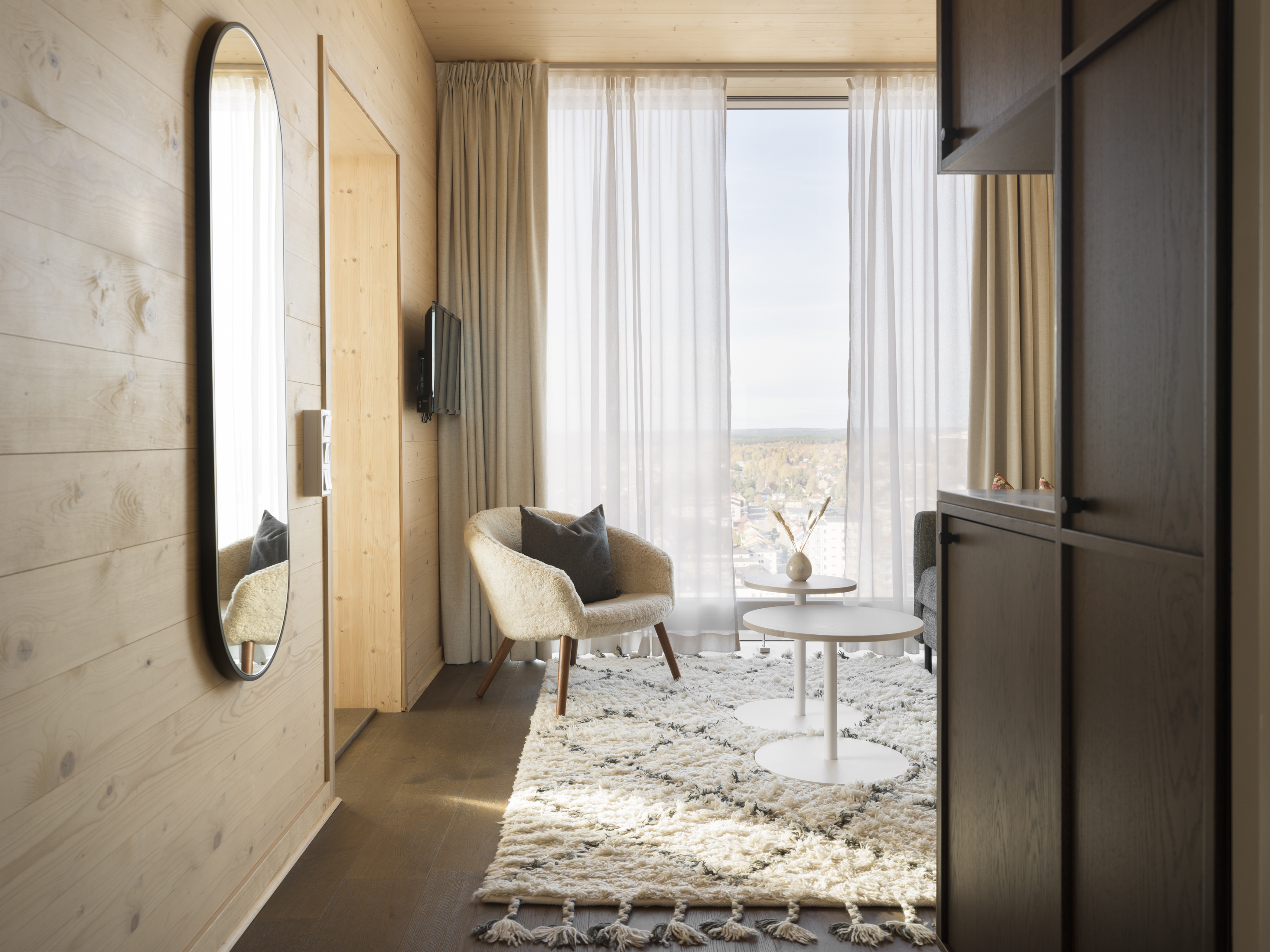 Mysigt hotellrum med säng, fåtölj och stort fönster