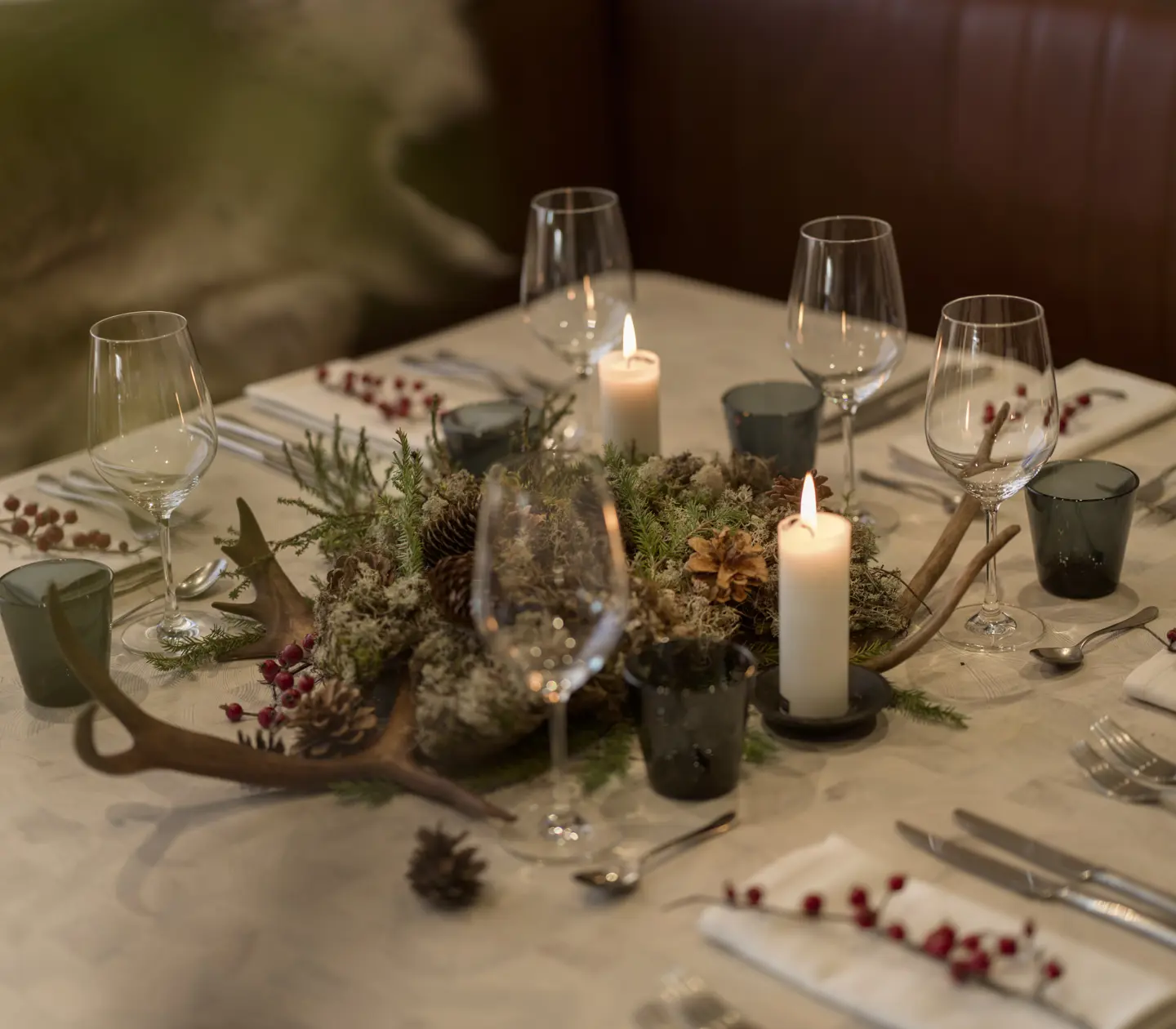 Dukat matbord i rustik restaurangmiljö med levande ljus och bordsdekorationer, omgiven av träpaneler.
