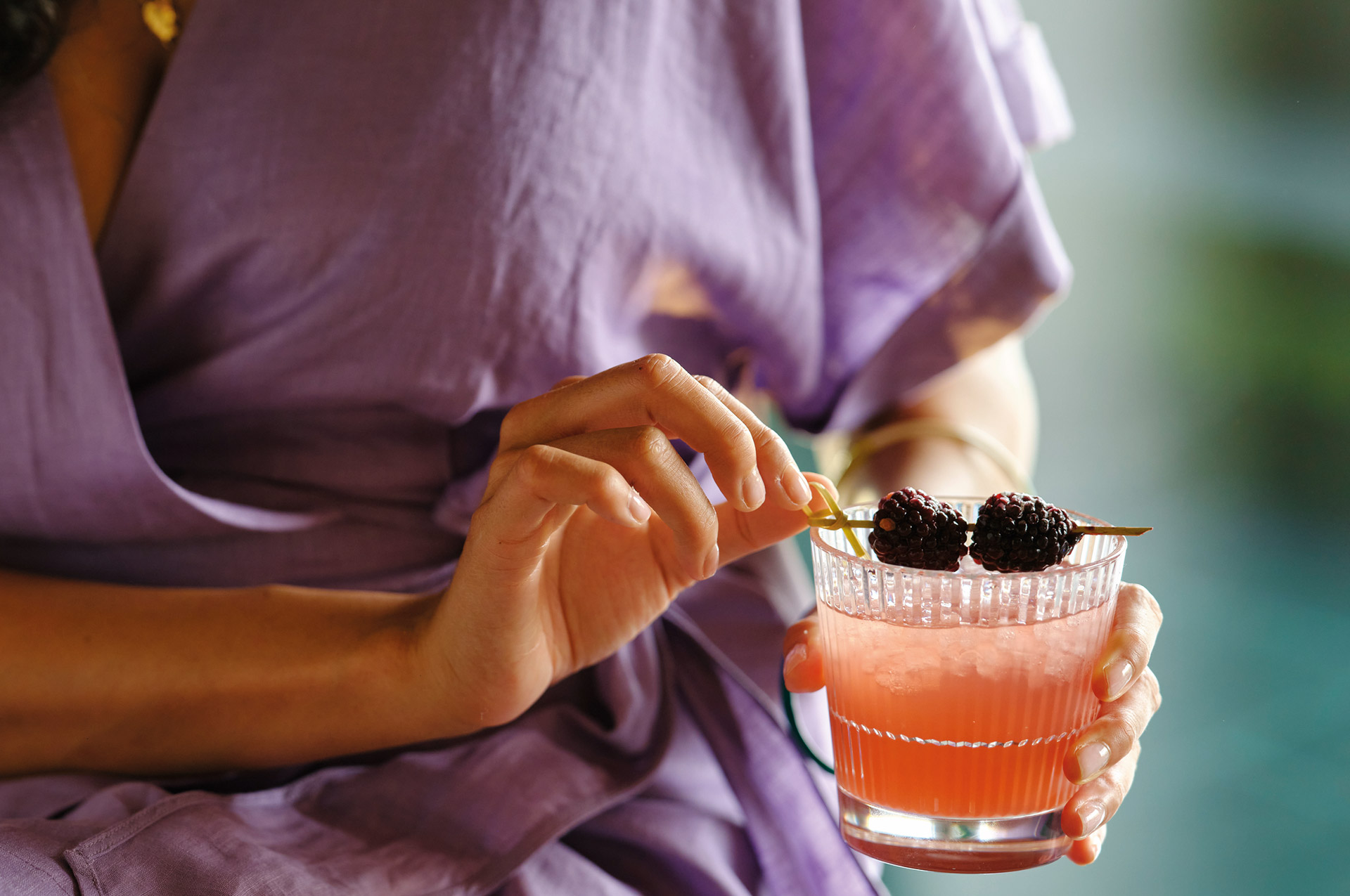 Kvinna i lila klänning med en drink i handen