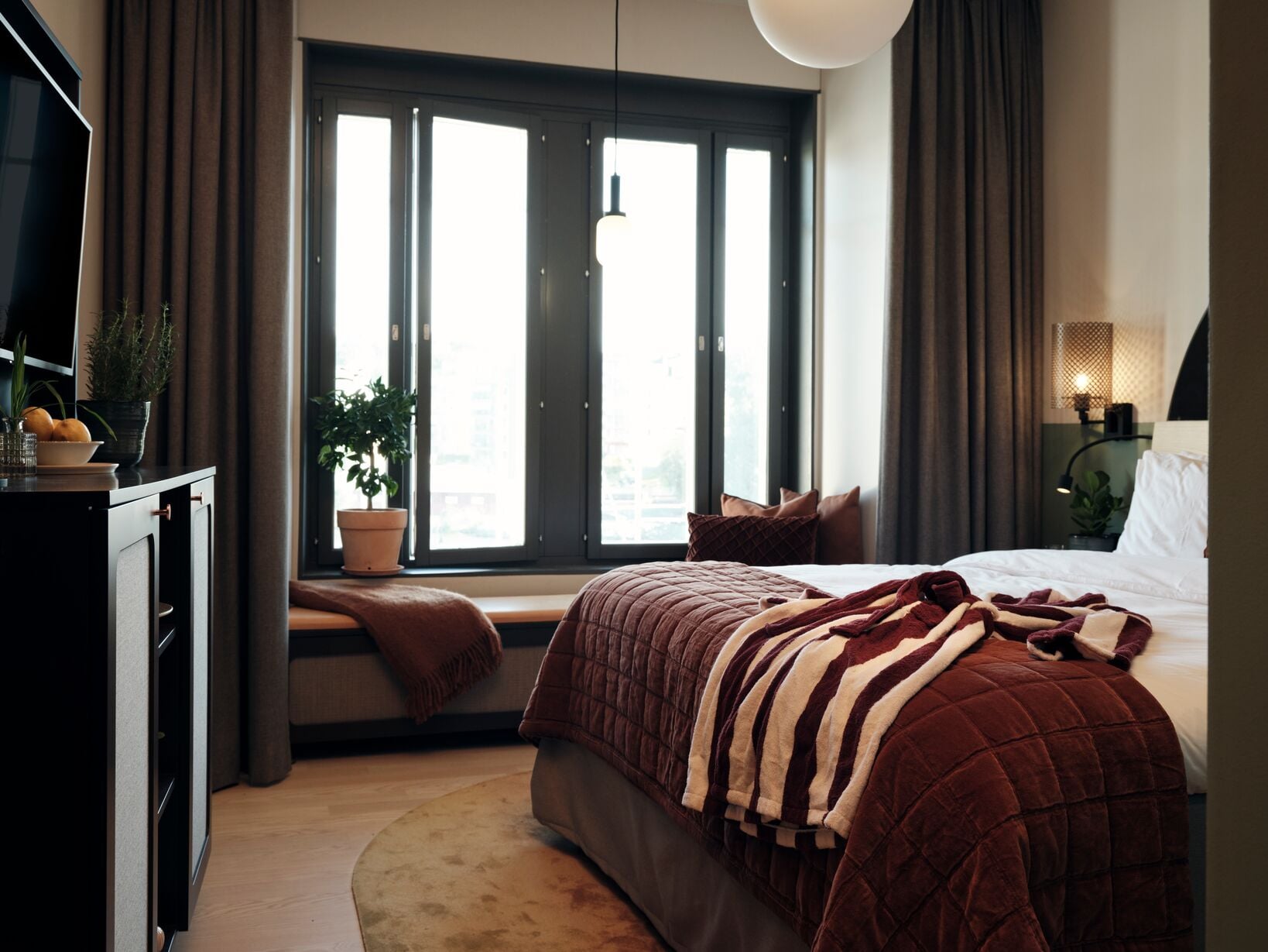 Mysigt hotellrum med säng, tv och stort fönster