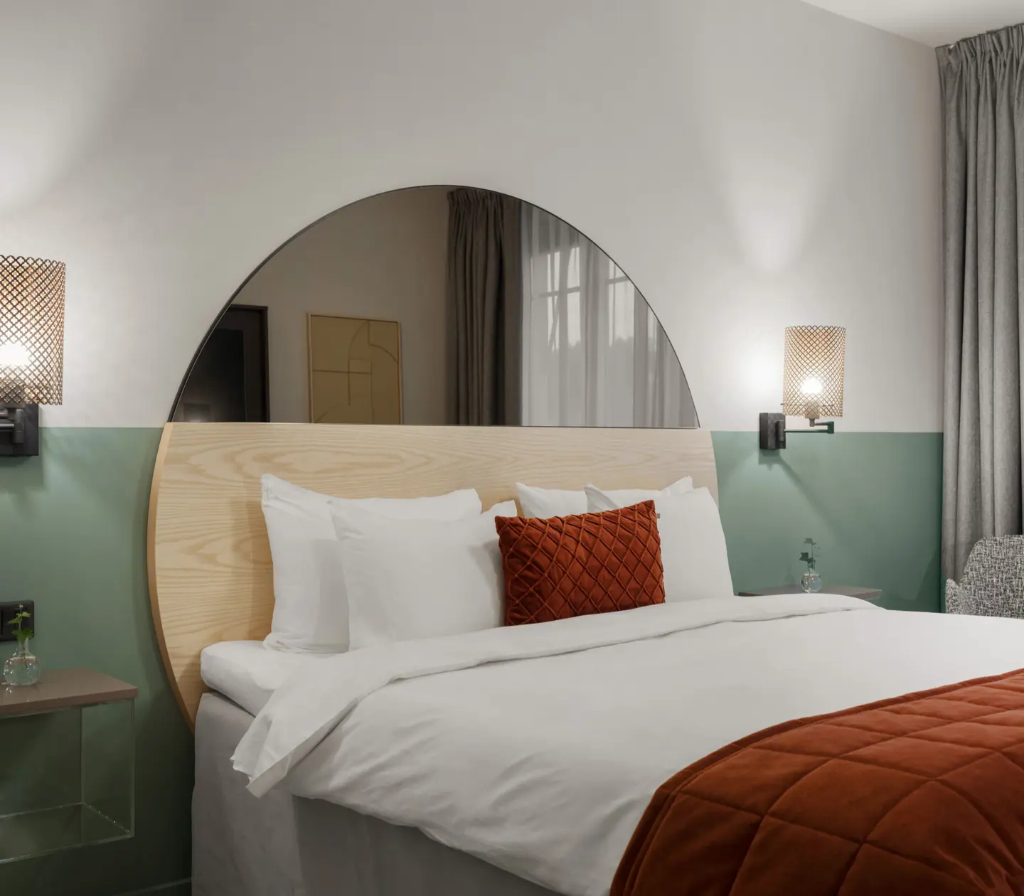 Mysigt hotellrum med säng, spegel och sänglampor