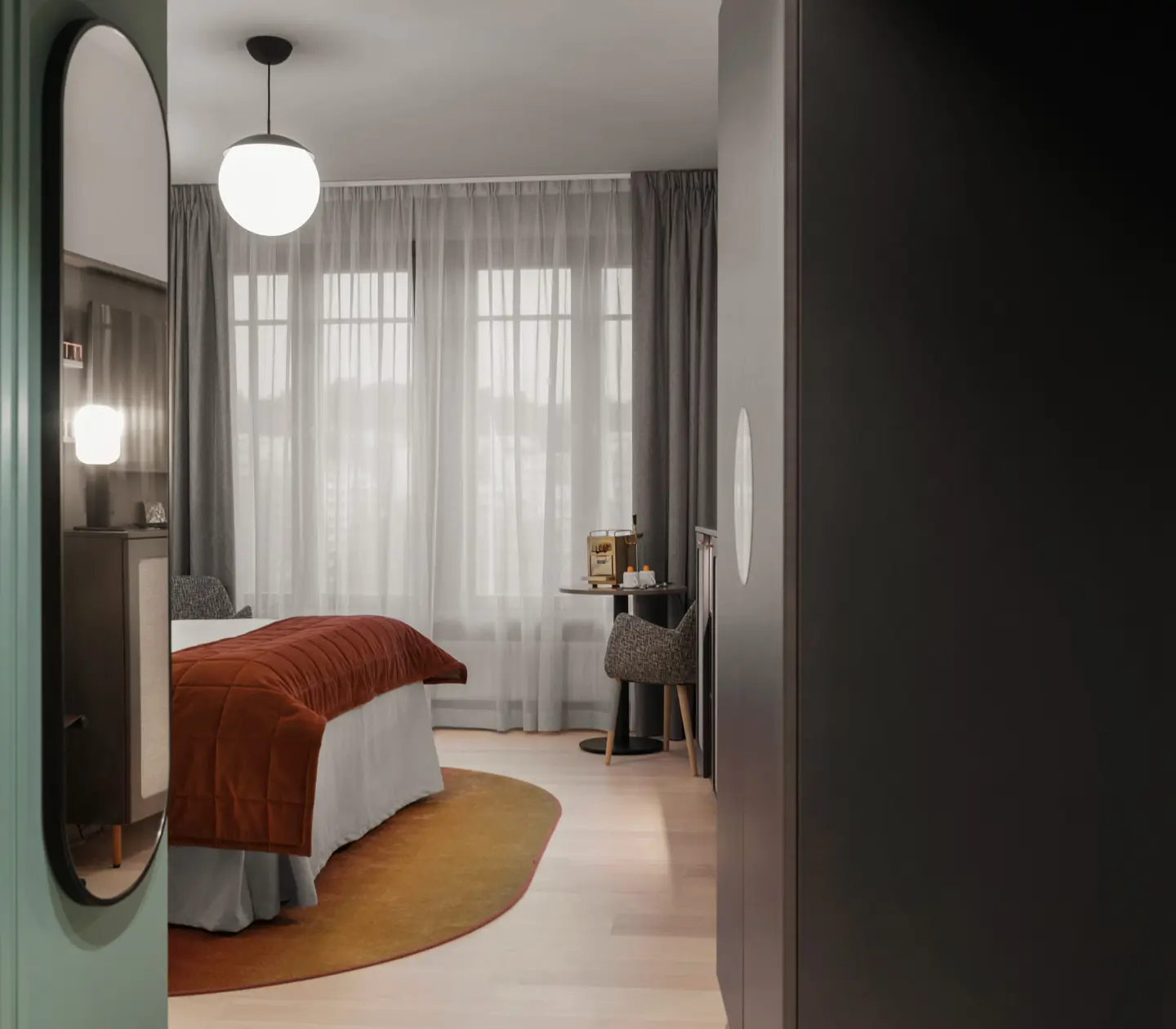 Mysigt hotellrum med säng, garderob och spegel