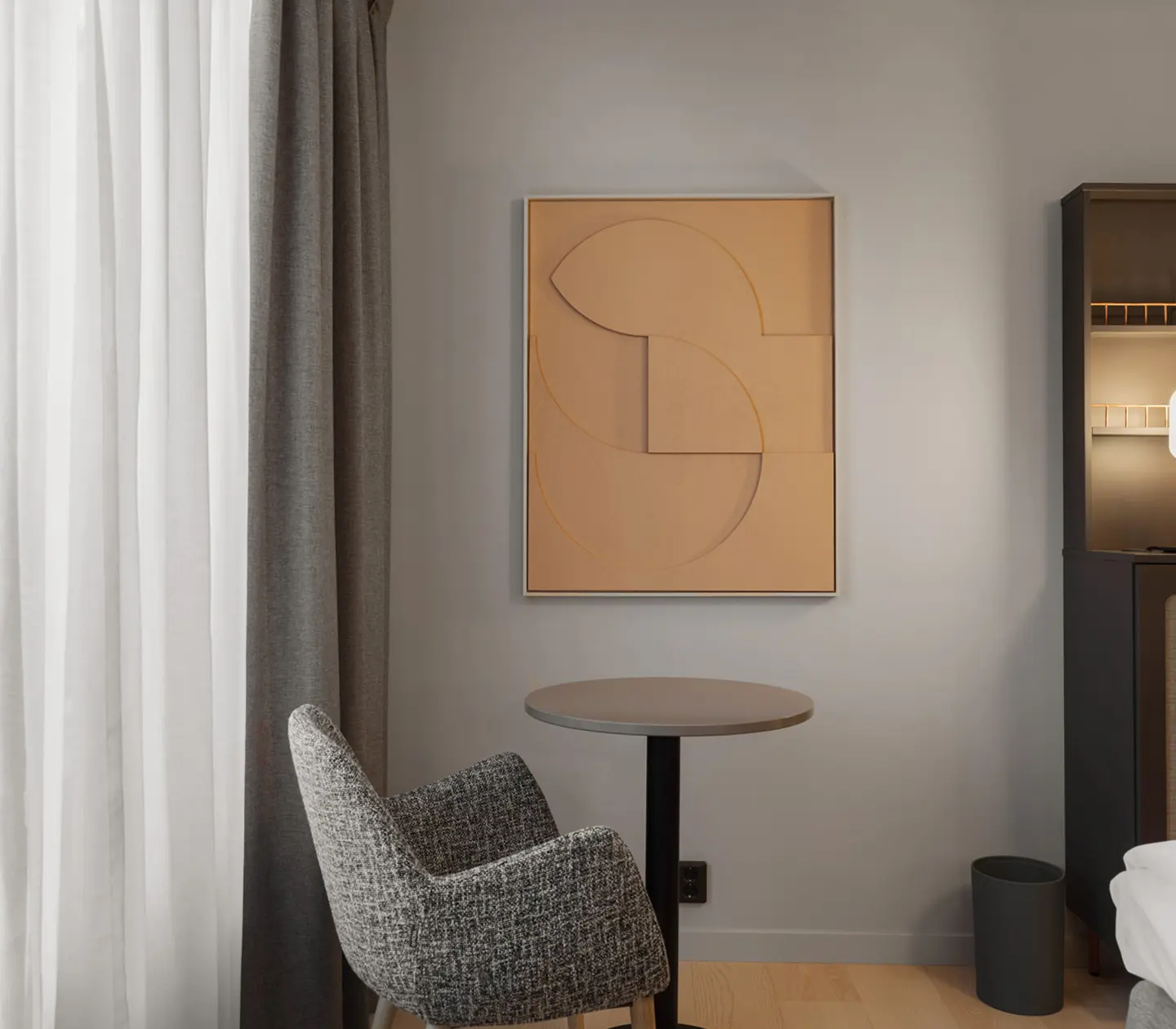 Mysigt hotellrum med fåtölj, tavla och gardiner
