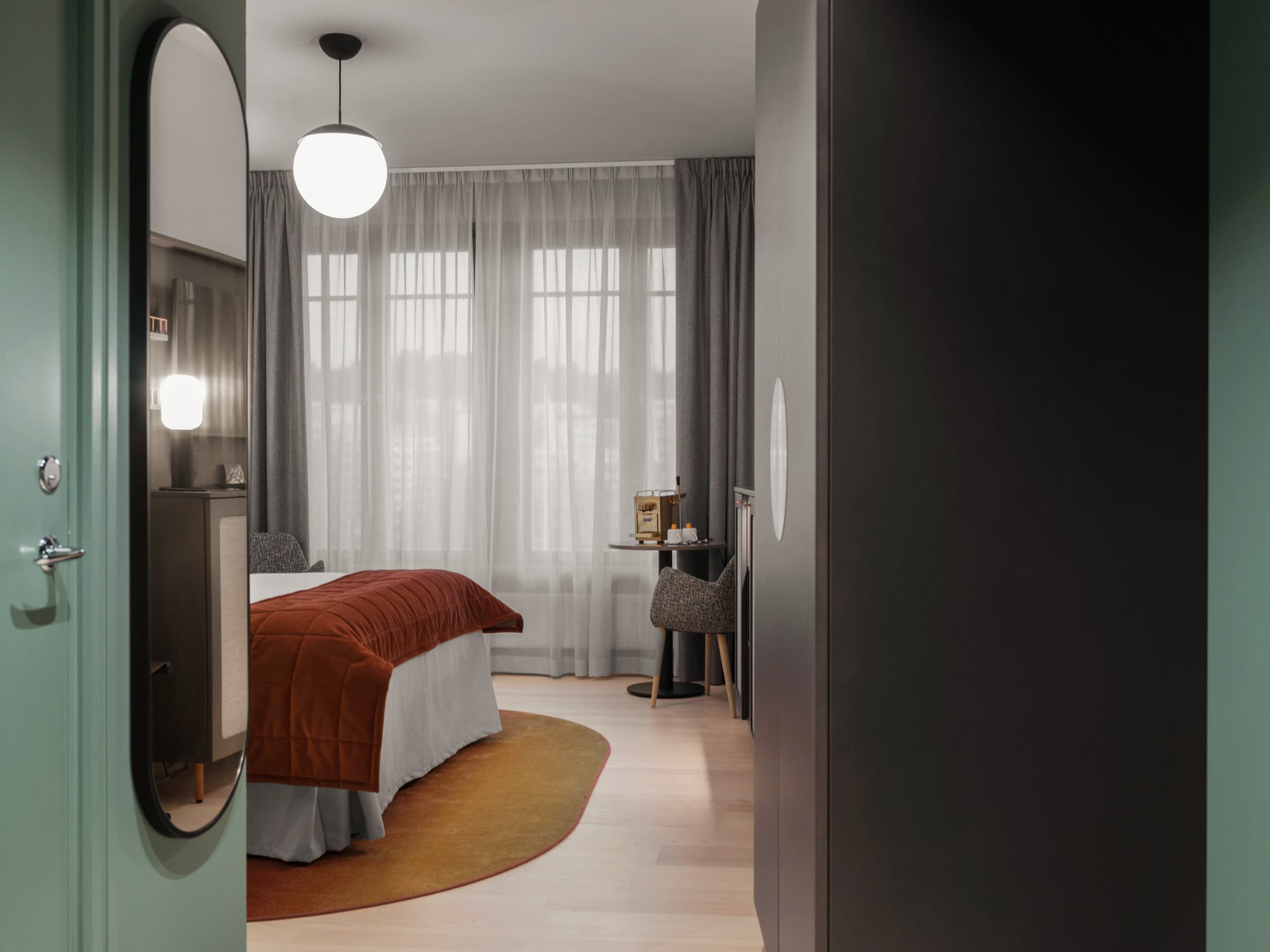 Mysigt hotellrum med garderob, spegel och säng