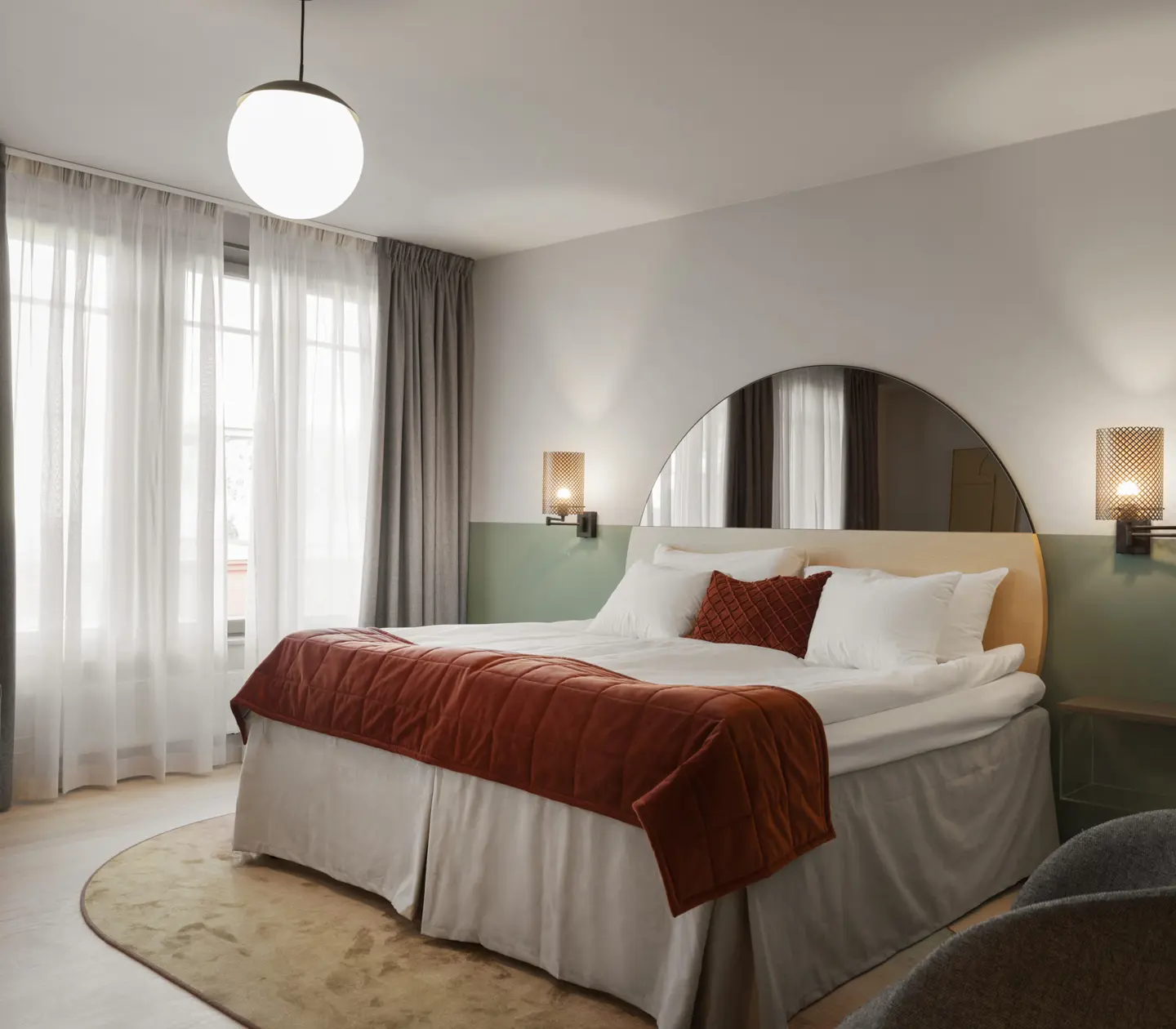 Mysigt hotellrum med säng, spegel och fönster