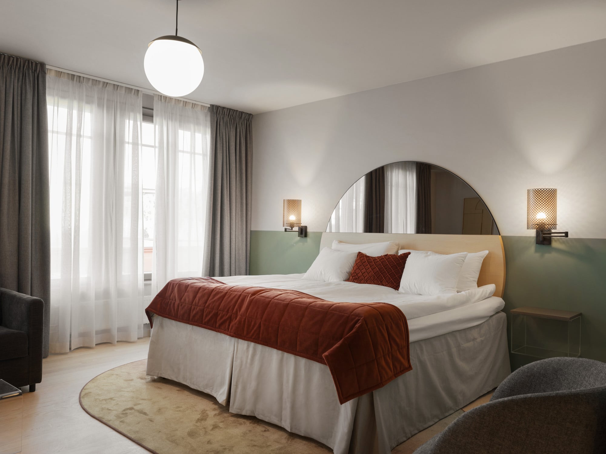 Mysigt hotellrum med säng, spegel och sänglampa