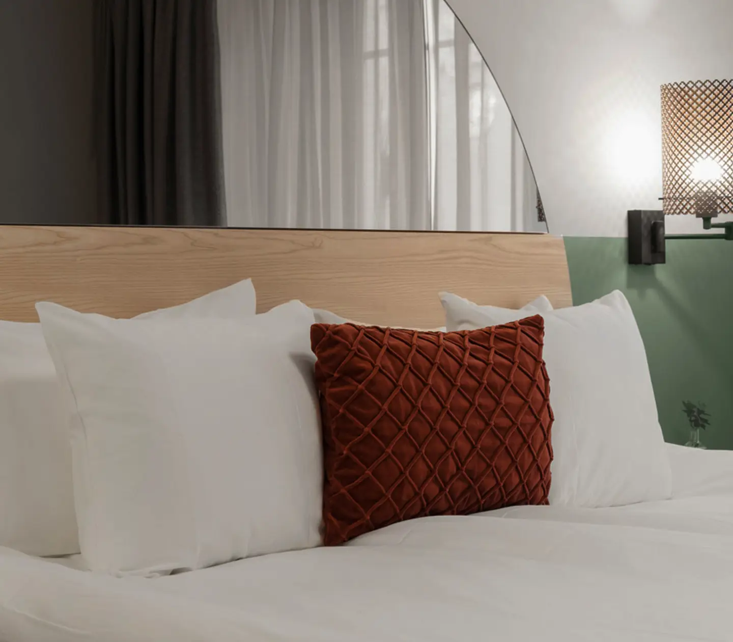 Mysigt hotellrum med säng, spegel och sänglampa