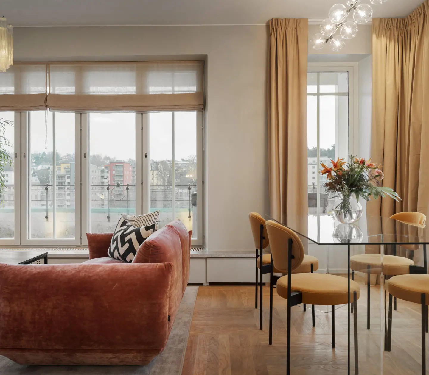 Mysig svit med rosa soffa, matgrupp och fönster längs väggarna