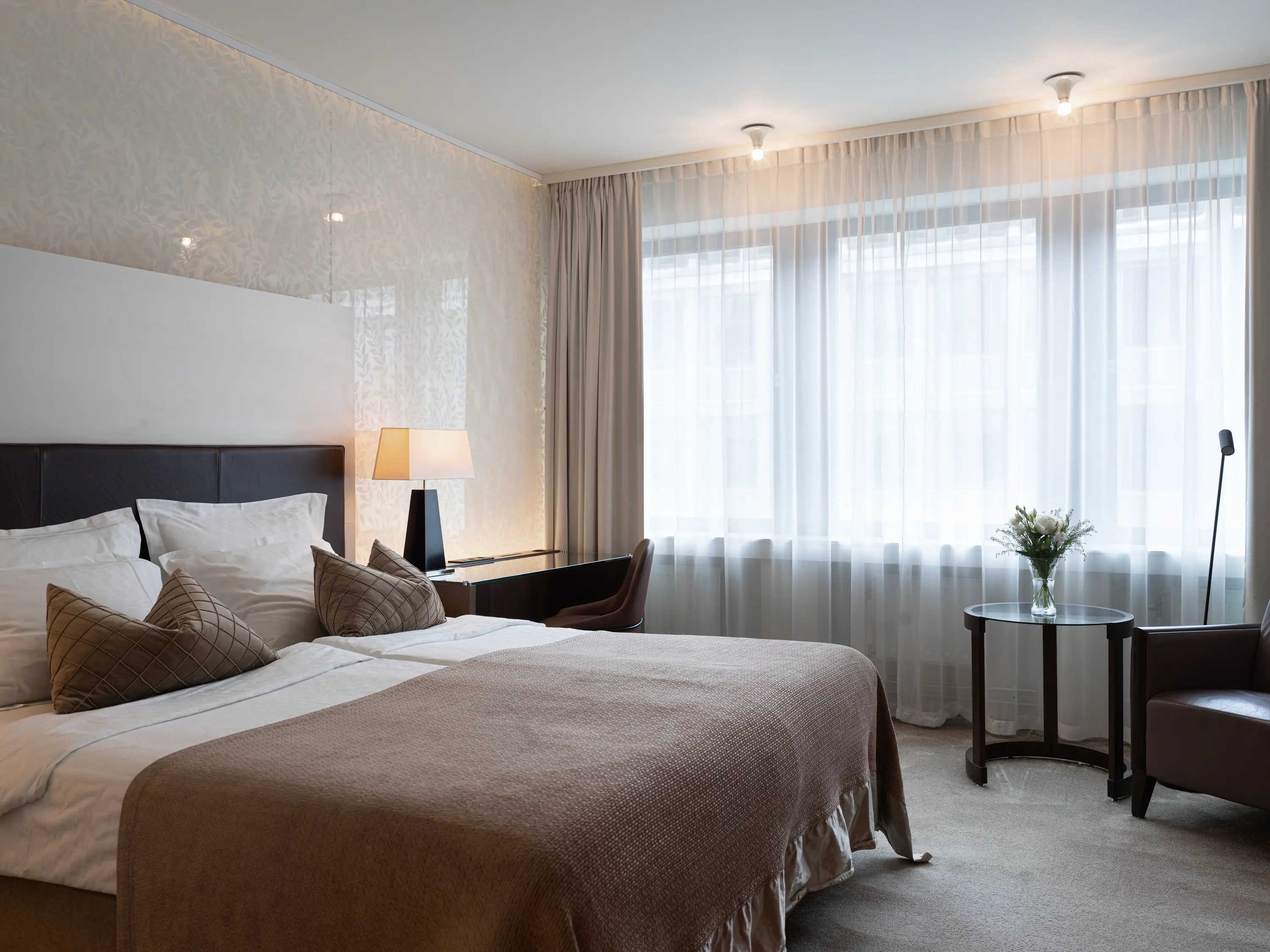 Ljust hotellrum med säng, skrivbord och fönster