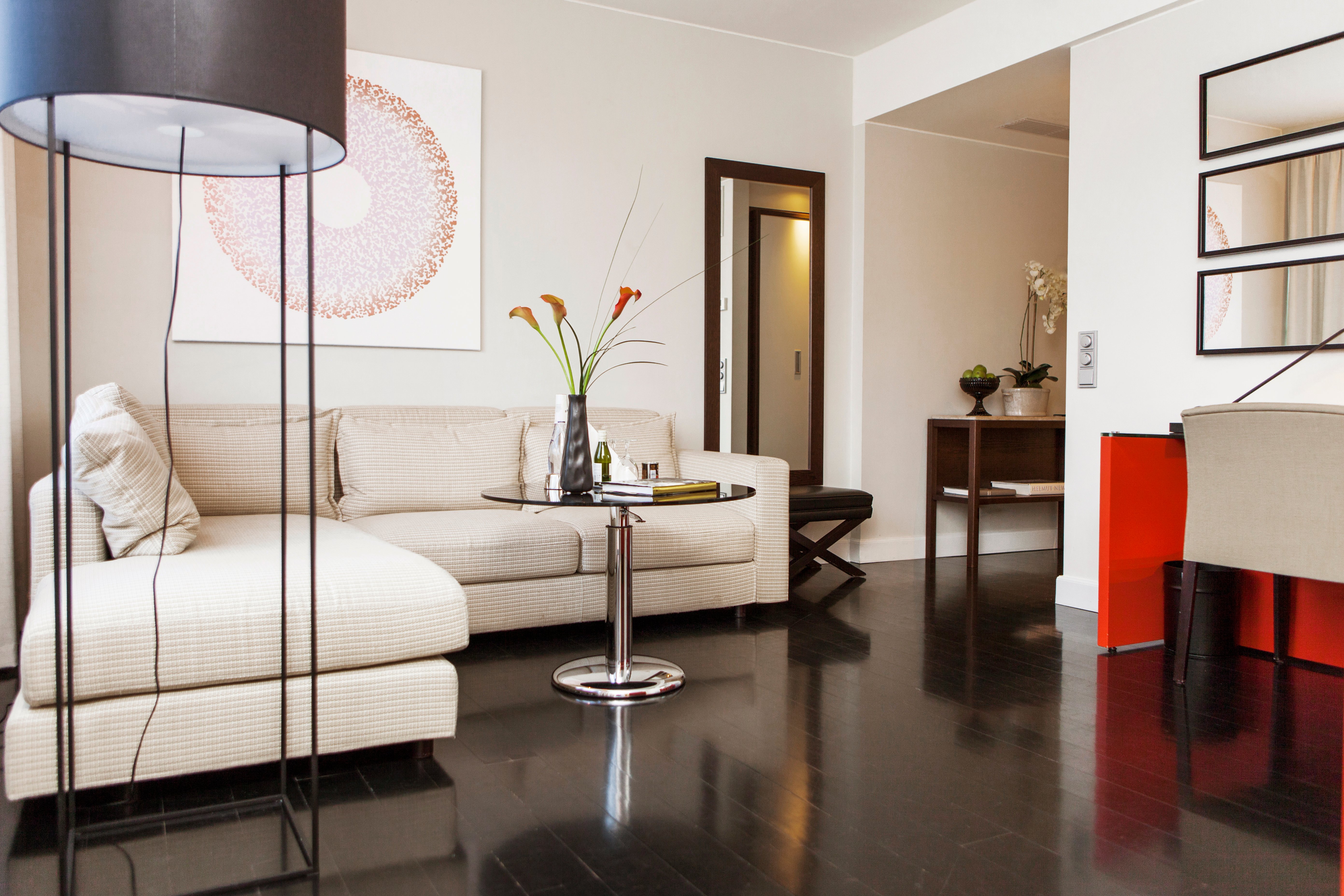 Bright hotel room with sofa, mirror and floor lamp