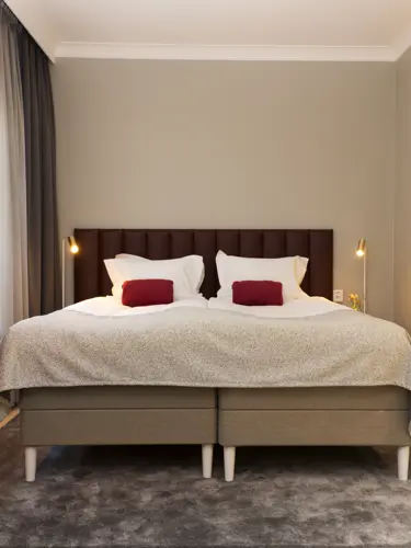 Mysigt hotellrum med dubbelsäng, fåtölj och golvlampa