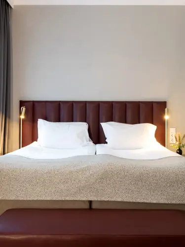 Hotellrum med säng, tavla och fönster