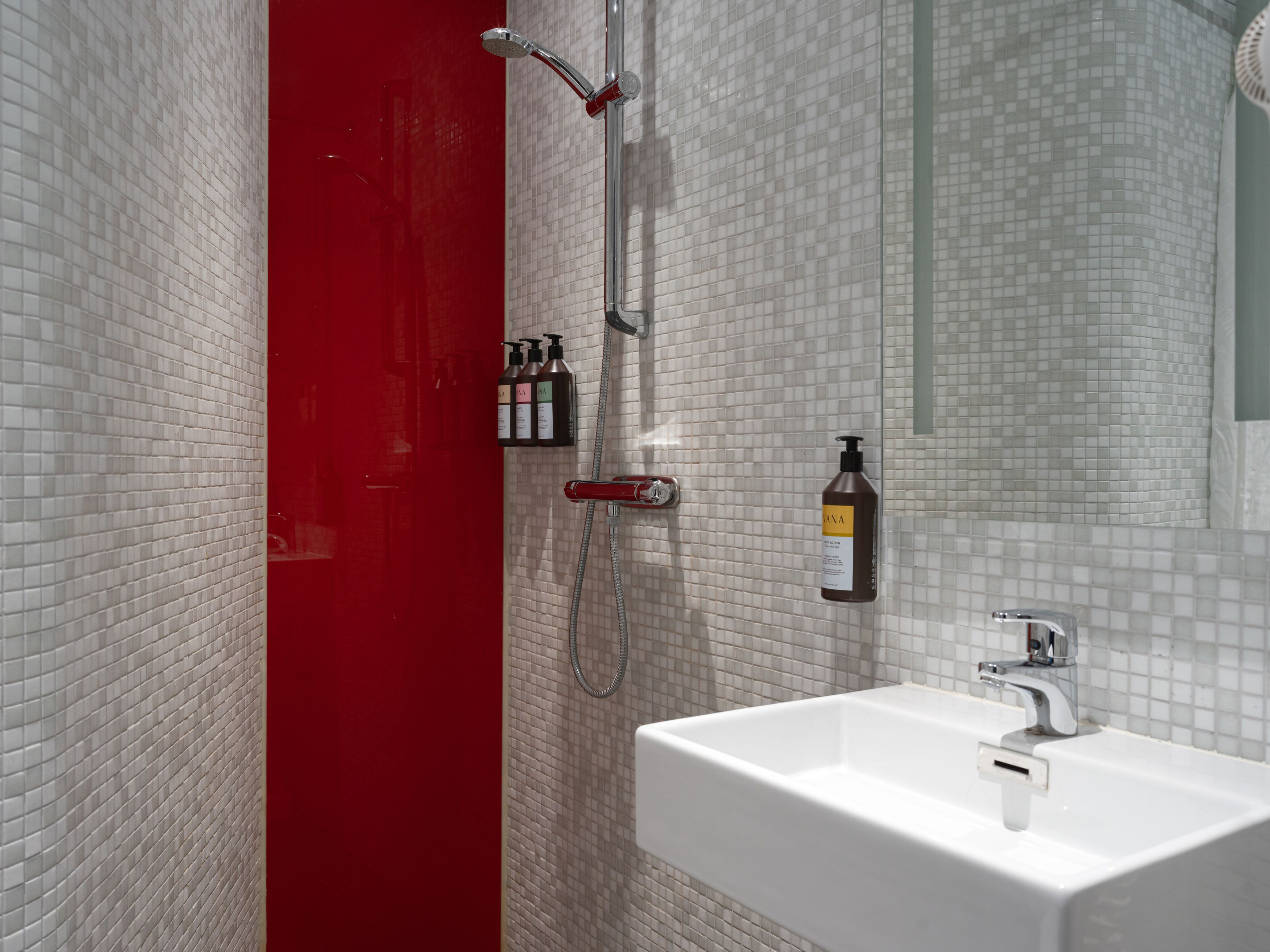 Ljust hotellrum med säng, orange textilier och skrivbord